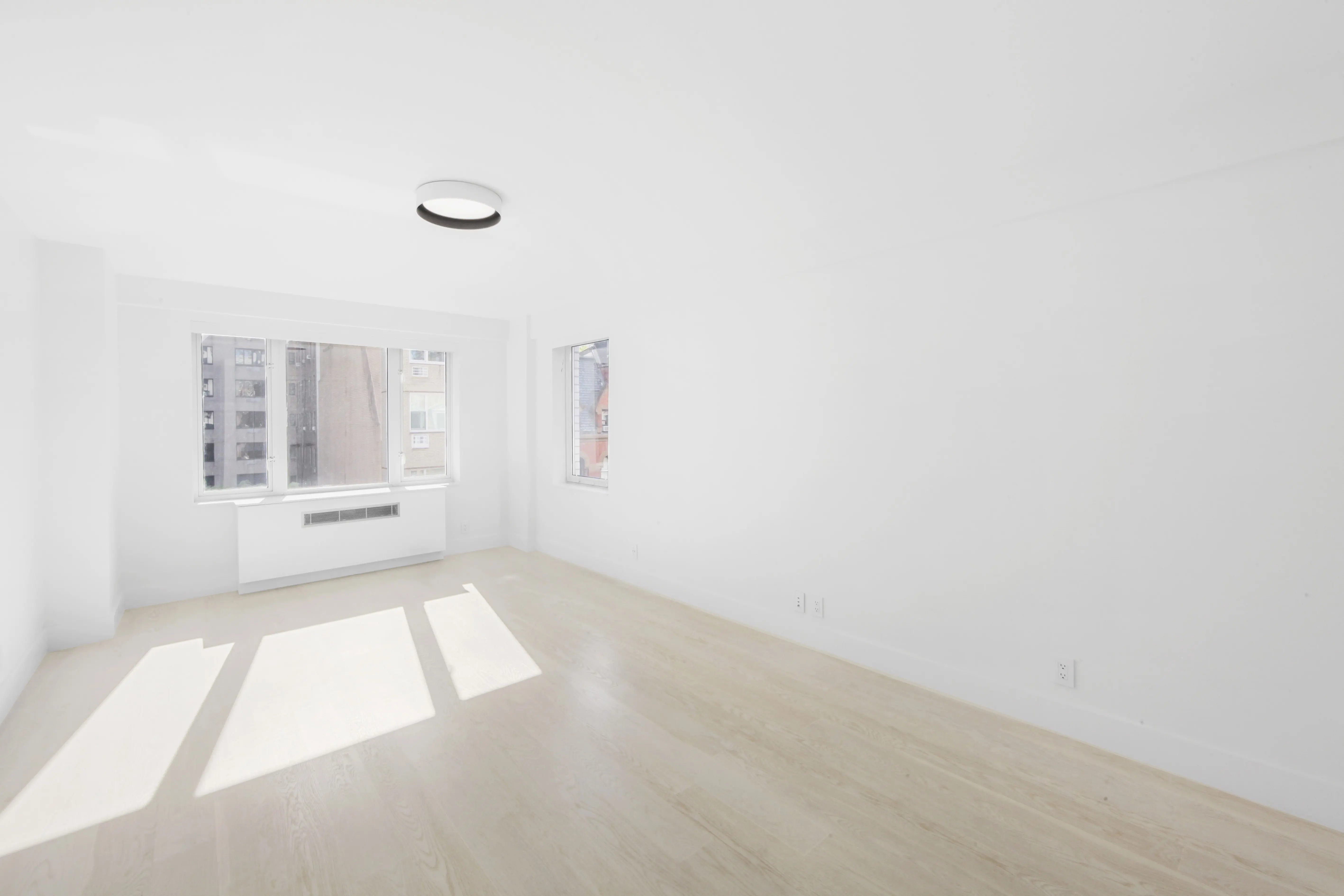 A vacant room with clean white walls and smooth hardwood flooring, offering a minimalist and open feel.