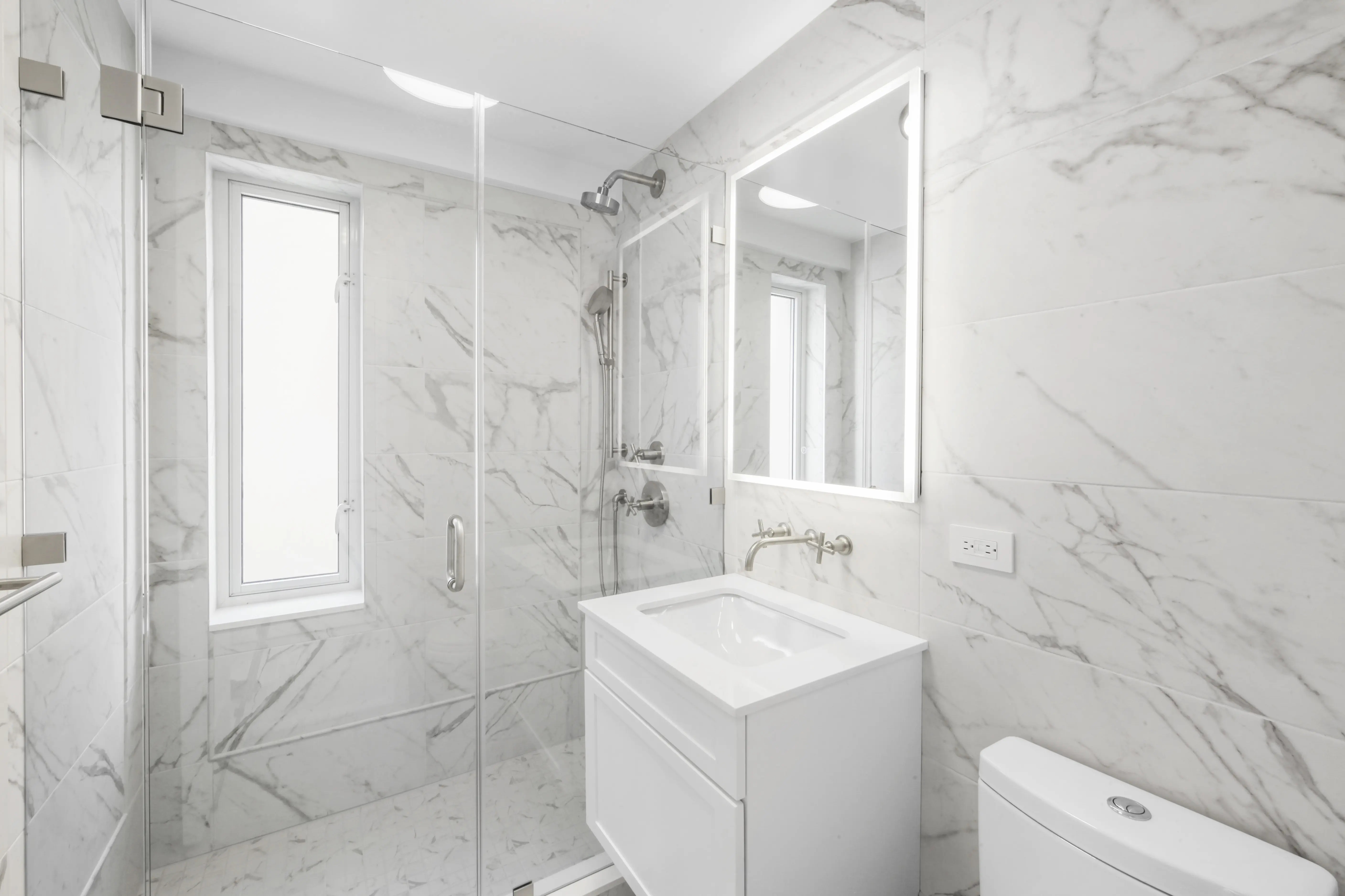 A stylish bathroom with polished marble walls and flooring, showcasing a sleek and upscale design.