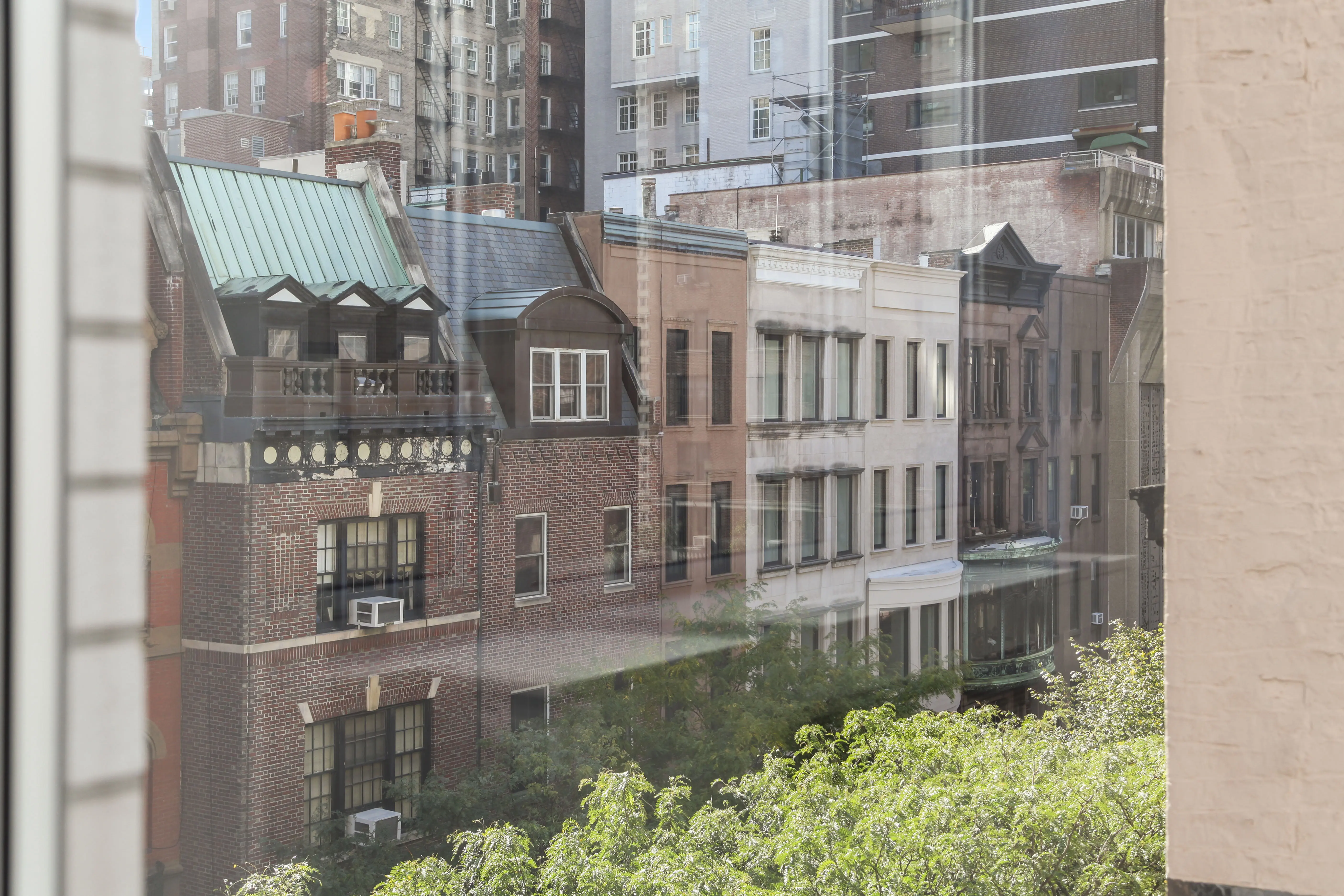 A window framing a vibrant cityscape, highlighting tall buildings and urban life.