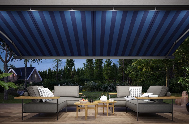Outdoor patio furniture set with blue striped awning and garden view.