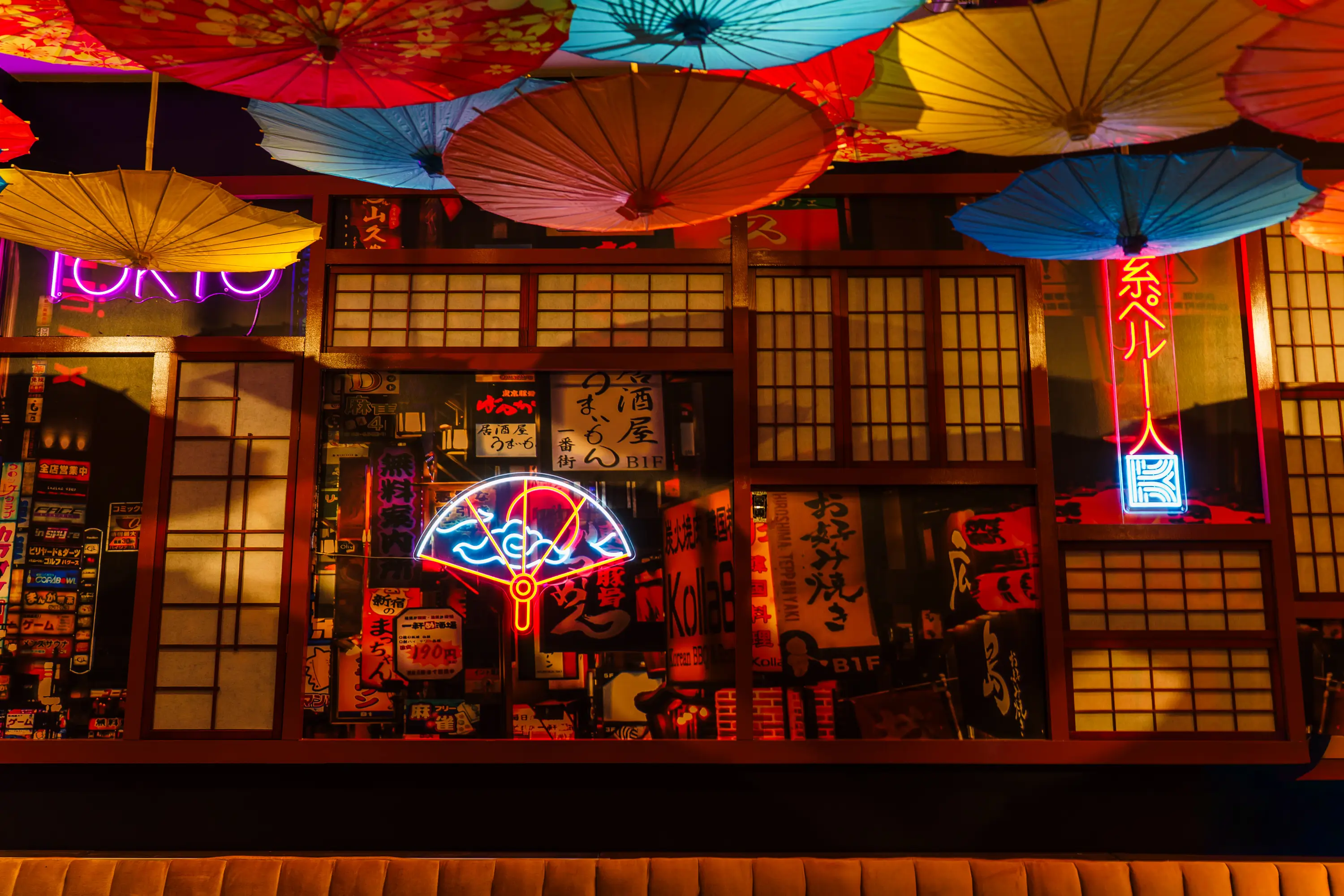 Rooftop bar at Kaiyō with a geometric green-tiled bar front and modern pendant lights. The bar is fully stocked and features a reflective countertop with fresh oranges on display