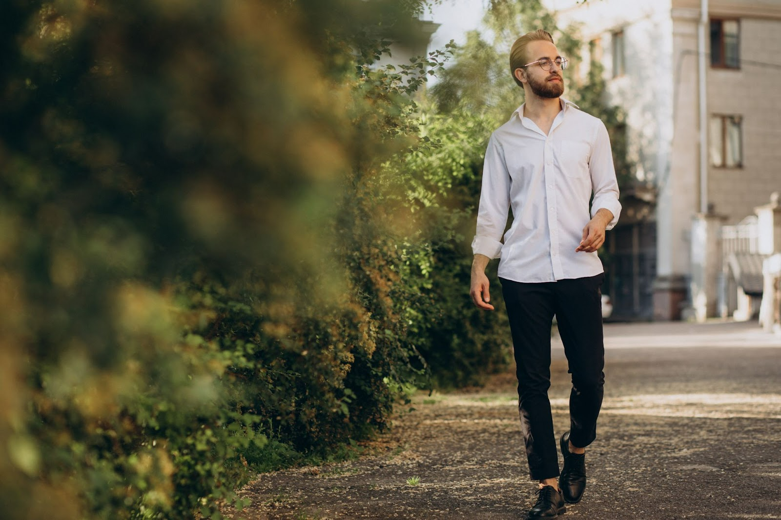 Confident young man walking outdoors in a white shirt and glasses, representing improved energy and well-being from TRT therapy