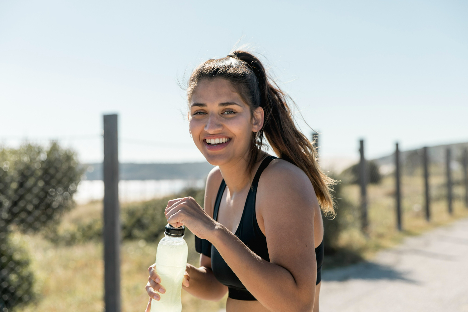 Smiling woman in athletic wear holding a water bottle after a workout, representing active lifestyle changes supported by Ozempic