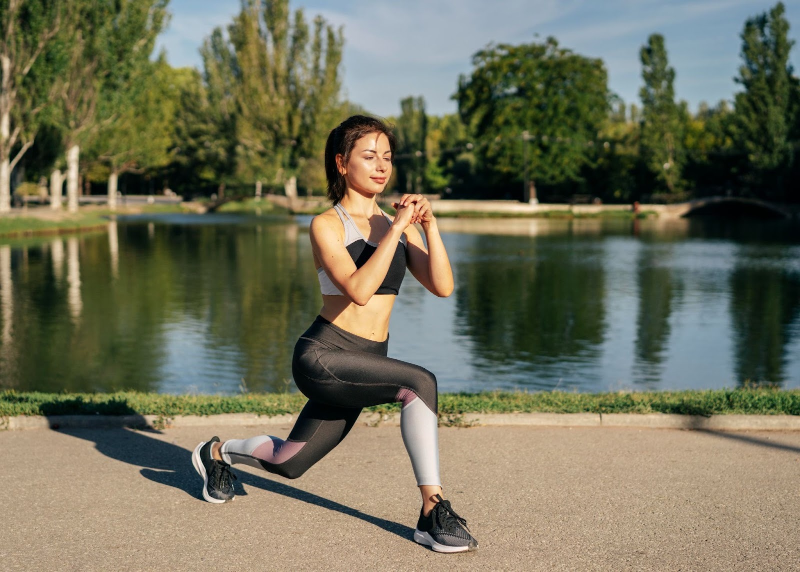 A healthy and fit woman stretching by a man-made lake in a park
