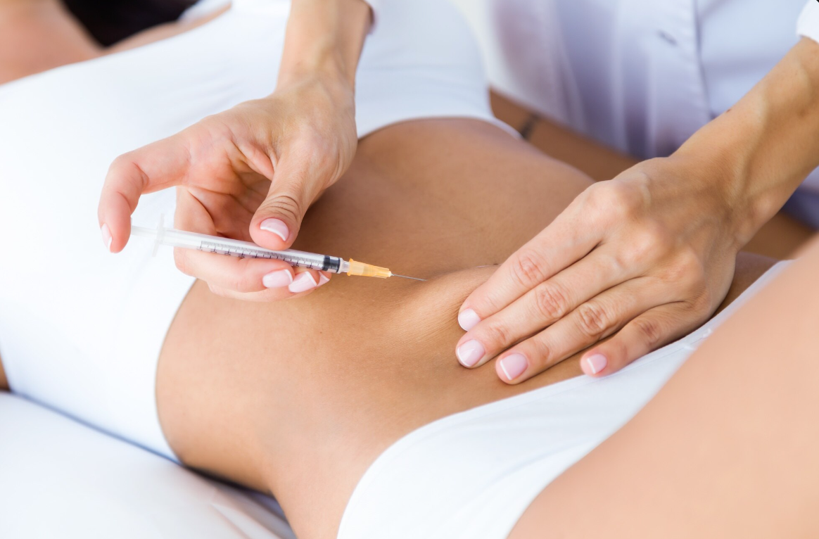 A close up shot of a slim woman getting injected at the abdomen area