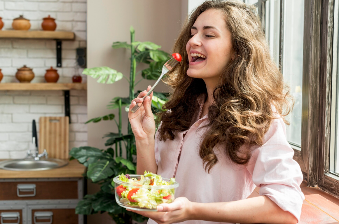 A woman eating healthy salad in a kitchen