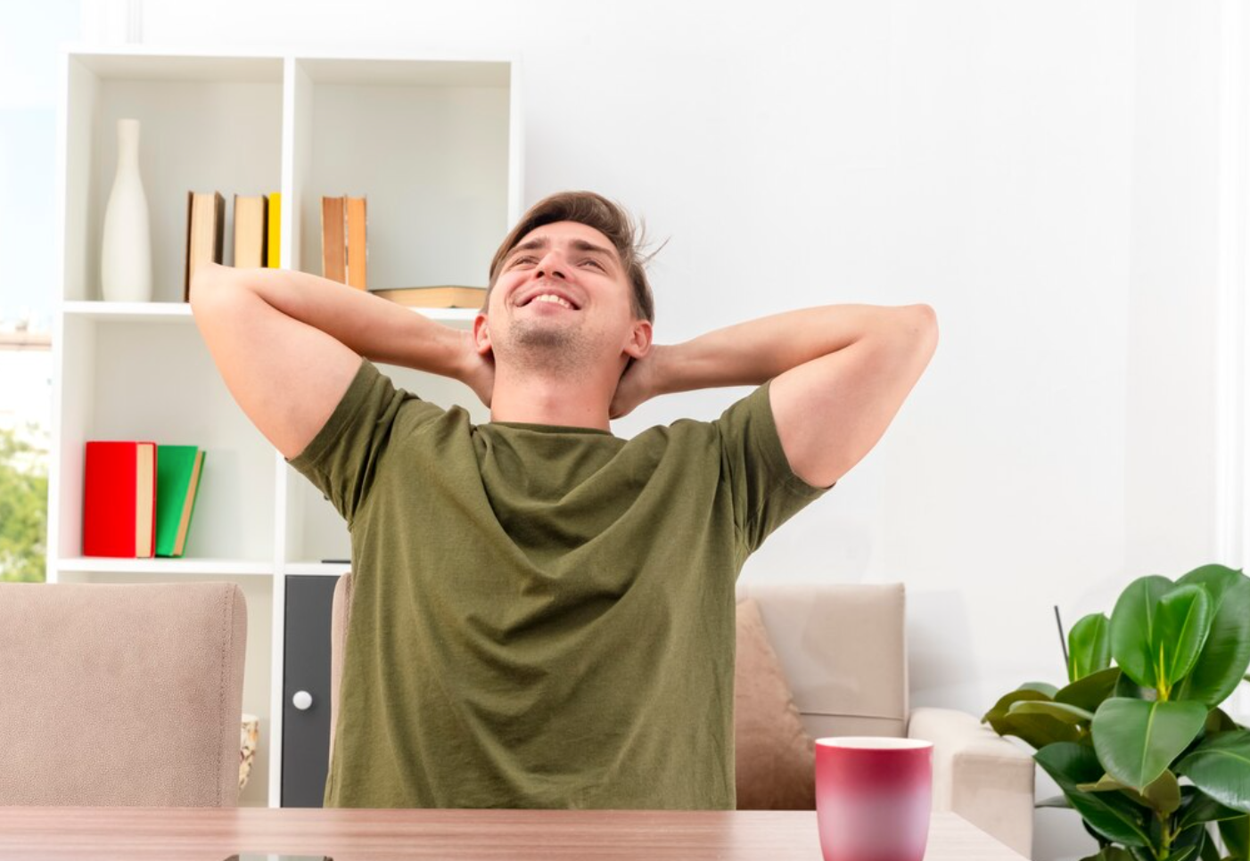 A smiling man, sitting down and ooking up with his hands behind his head, thinking about the benefits of ketamine therapy