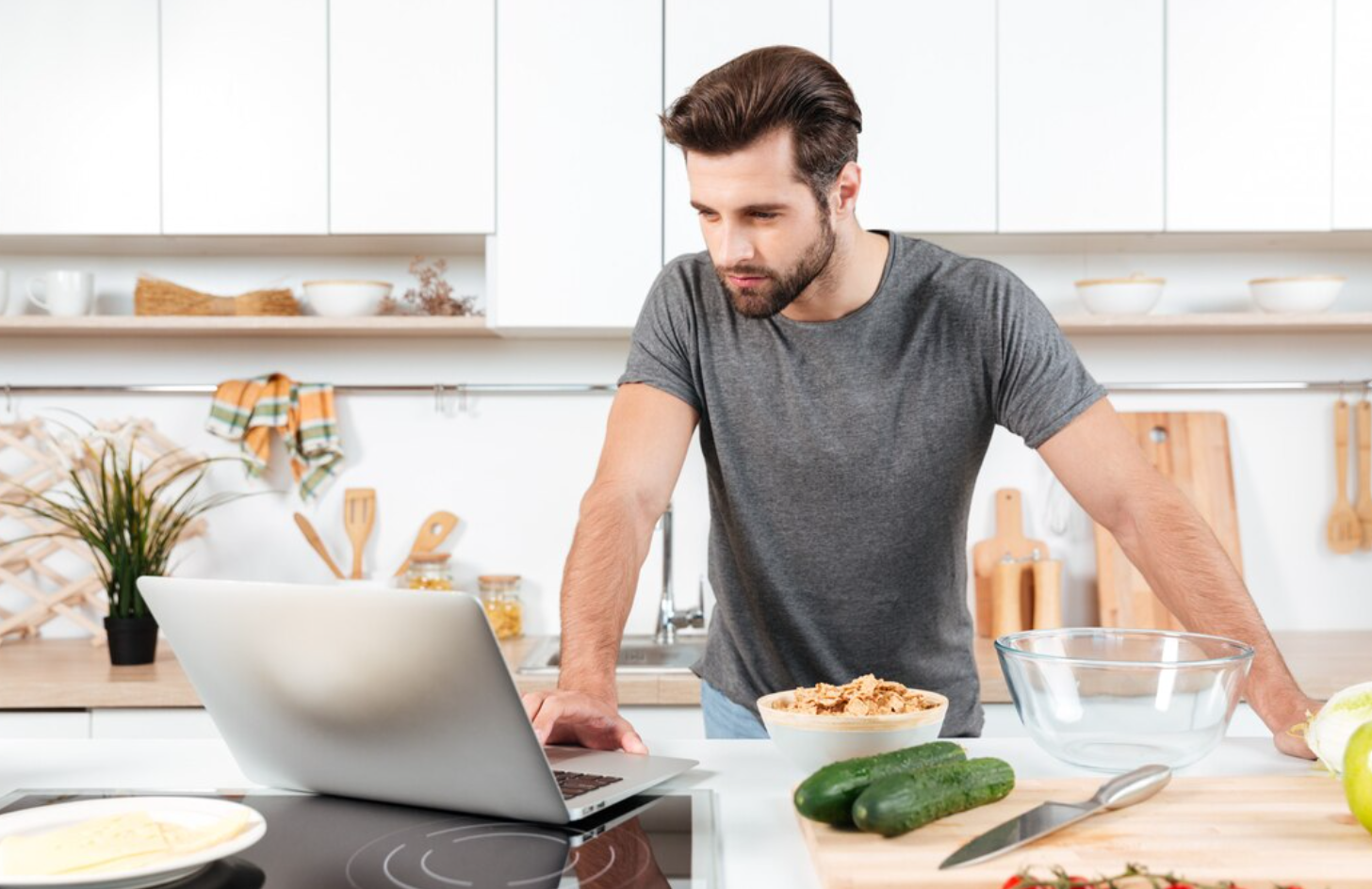 A searching something on a laptop while preparing healthy food, as advised by a Utah wellness clinic