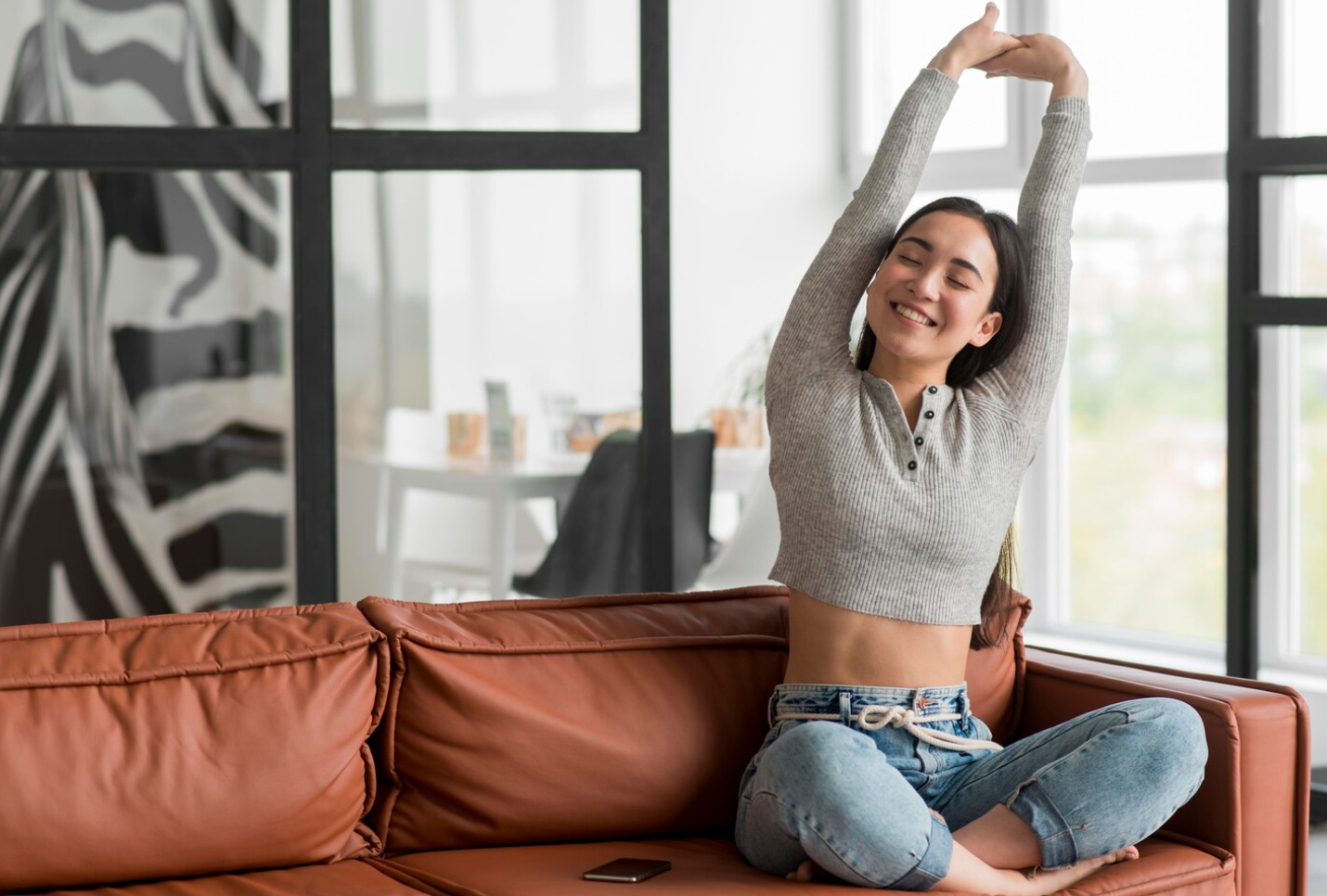A woman stretching and sitting on a couch, enjoying the benefits of semaglutide weight loss 