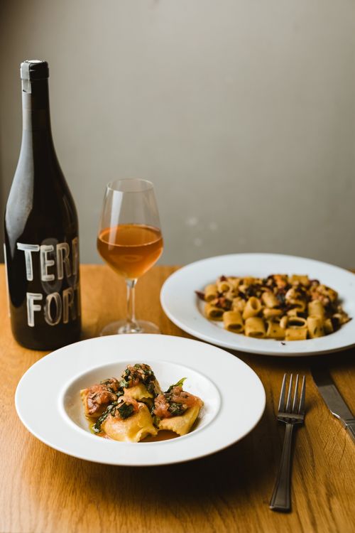natural wine bottle and pasta dishes on table inside giacco's