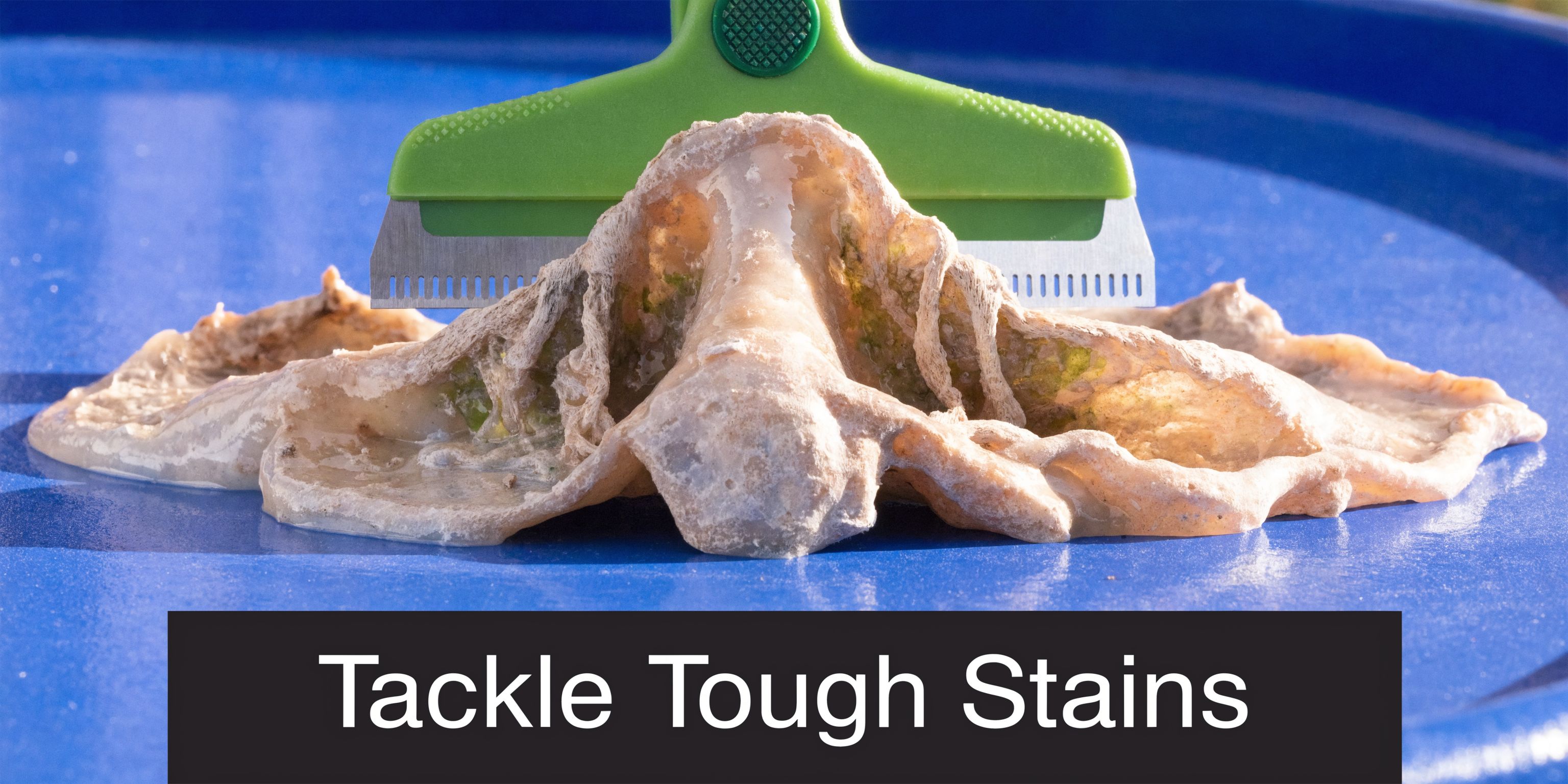 A green handheld scraper cleaning a dirty substance off a smooth blue surface, symbolizing heavy duty cleaning.