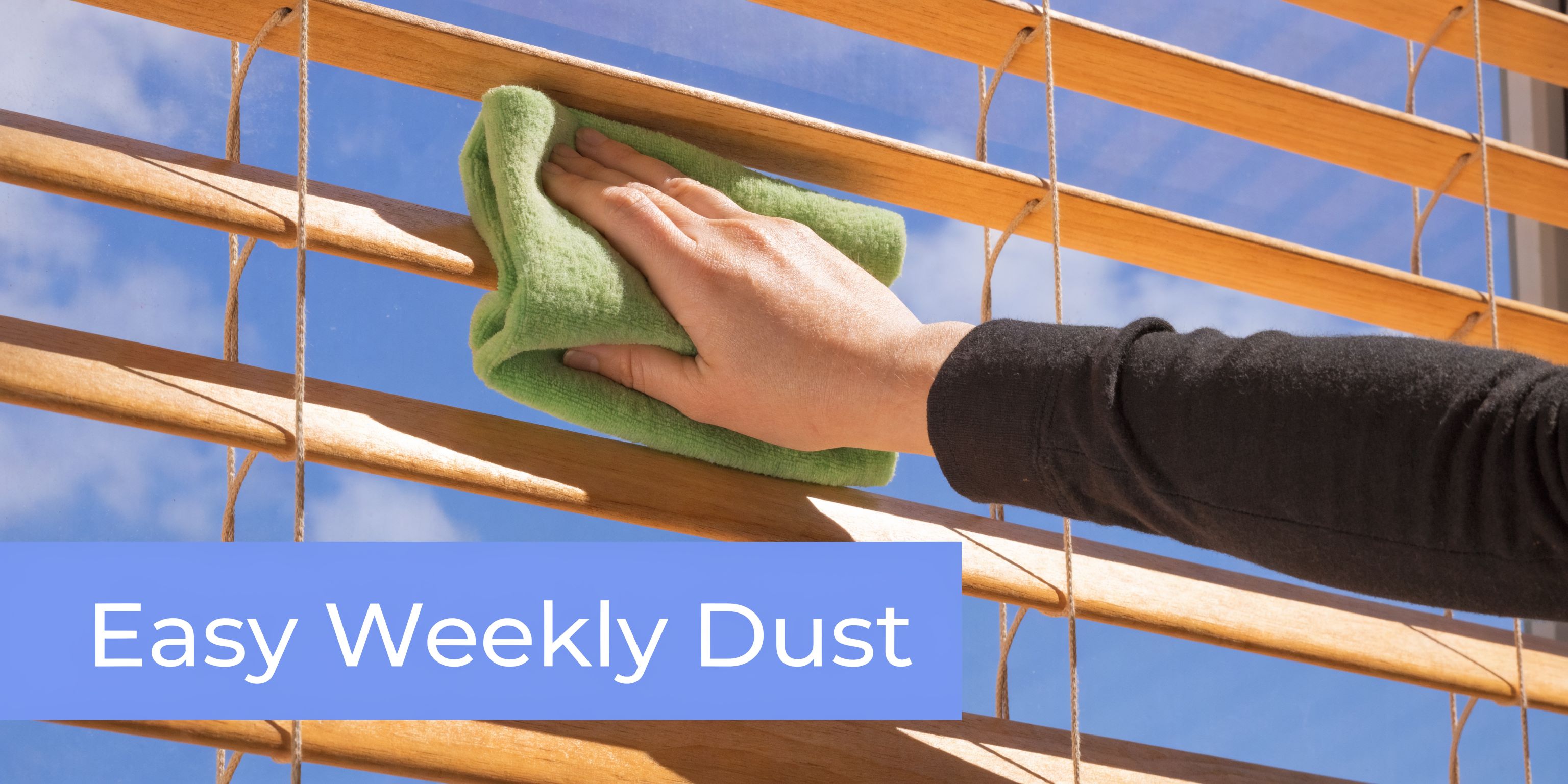 A person cleaning wooden window blinds with a soft green cloth to remove dust.
