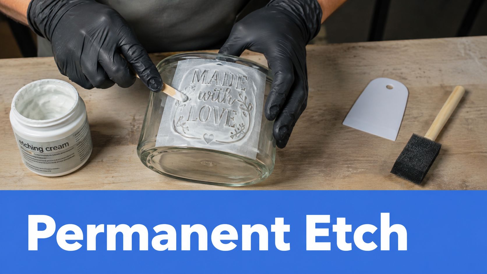A person wearing black gloves applying etching cream onto a glass jar with a stencil design.