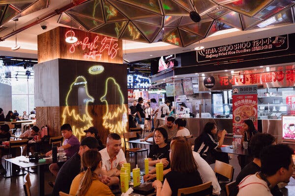 People sit at tables in a mall food court