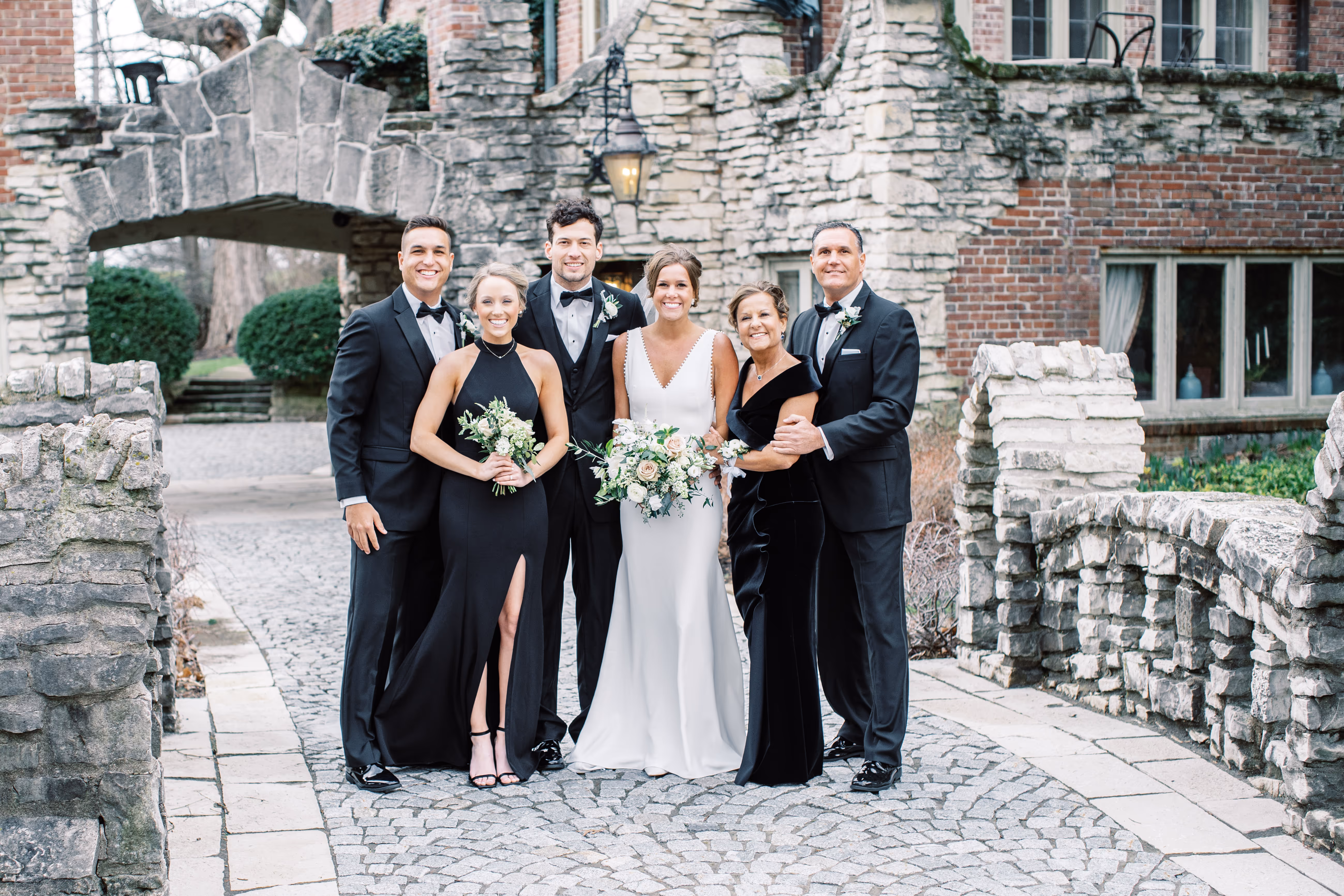 A wedding group is standing on the Castle's bridge for their wedding photoshoot.