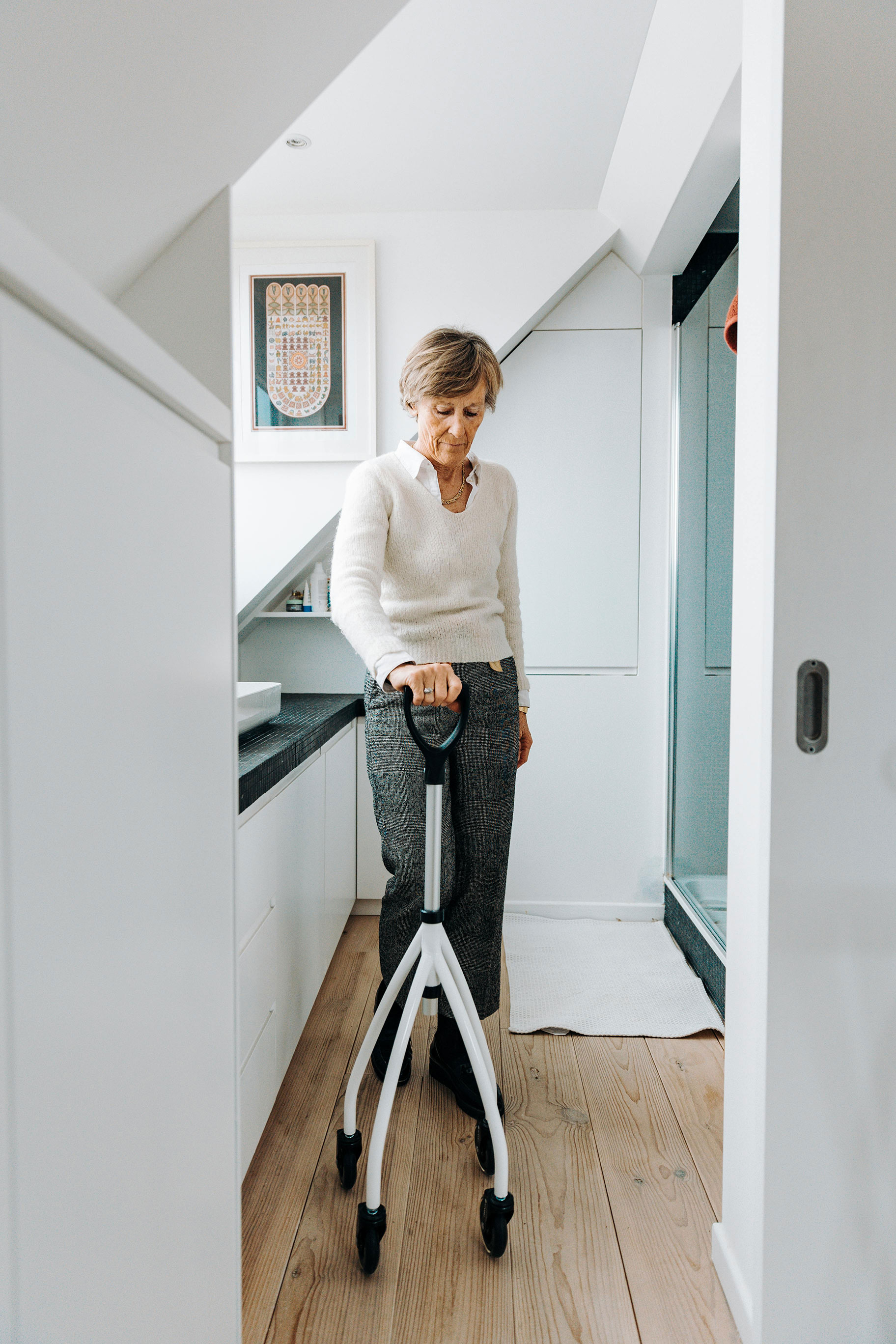 Traveler walking through a narrow alley in front of an ornate wooden Moroccan door, surrounded by traditional mosaic tiles and a display of handcrafted leather bags. The scene captures authentic Moroccan architecture and artisan culture in a historic medina.