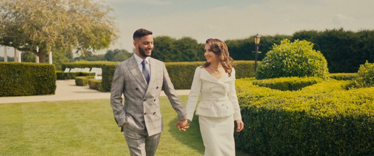 A couple walking hand in hand through the gardens at Froyle Park