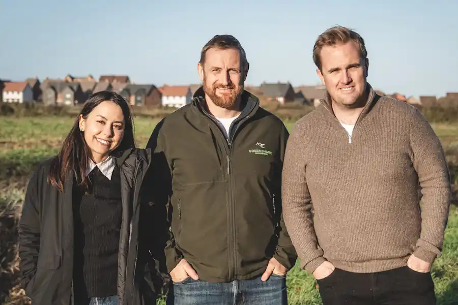 Grace Pinault, Kim Connor-Streich and Oliver Davis in a field at Stodmarsh with new housing behind