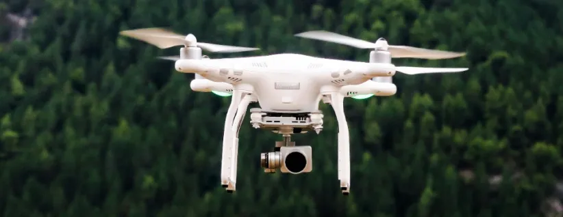 Drone hovering against a backdrop of trees