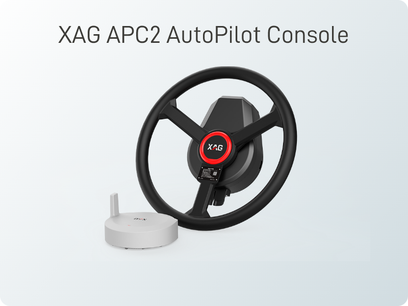 XAG APC2 AutoPilot Console with a black steering wheel and a small white device on a light background.