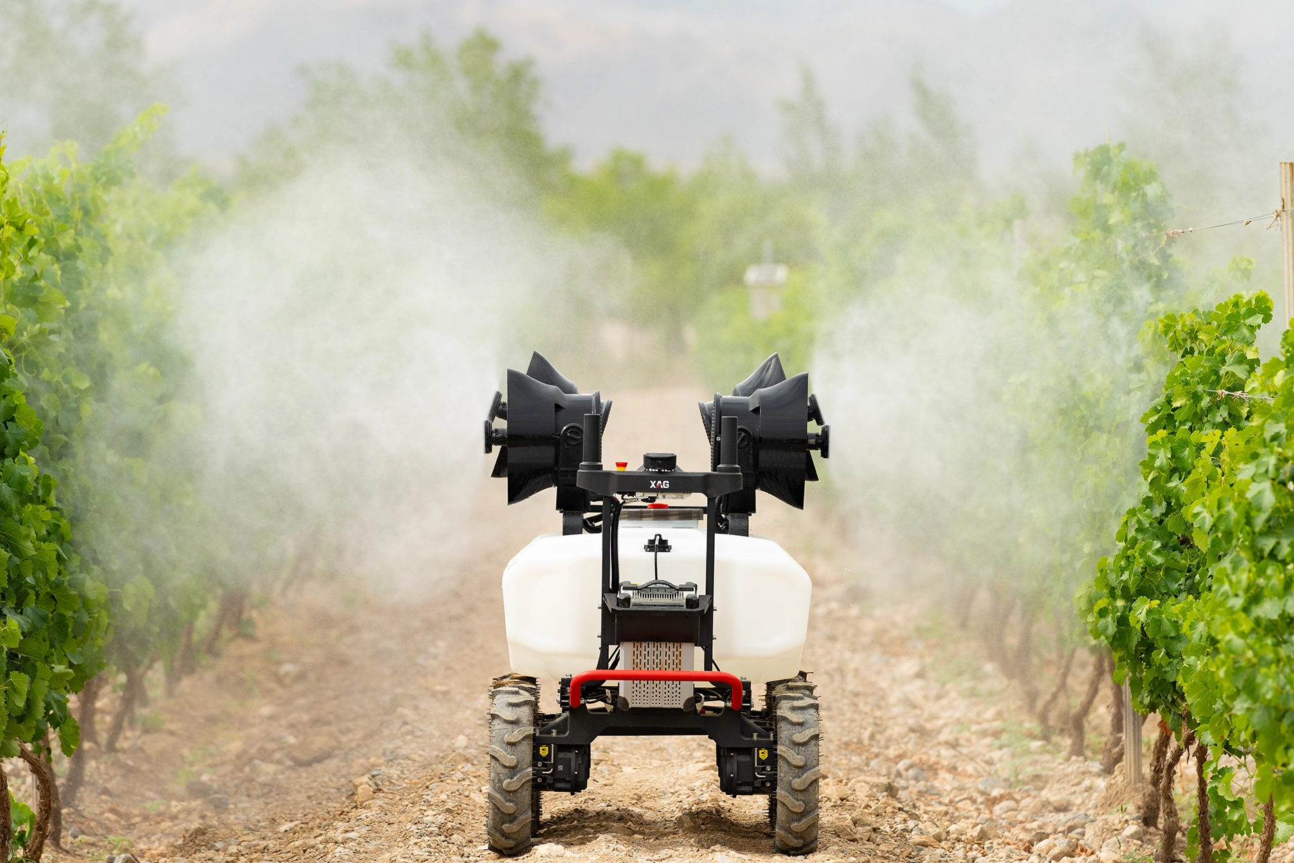 Six-wheeled agricultural robot with white tanks and black equipment on grassy field