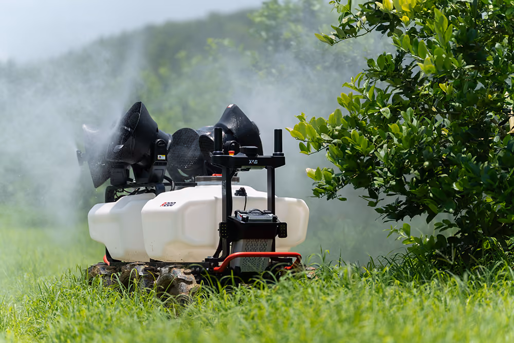 Six-wheeled agricultural robot with white tanks and black equipment on grassy field