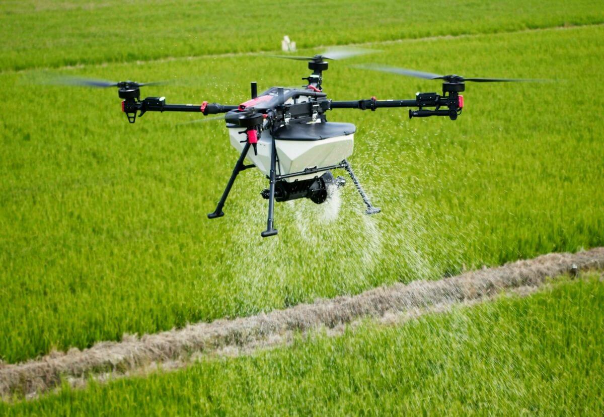 XAG P150 Max agricultural drone spreading granular material over a green field.