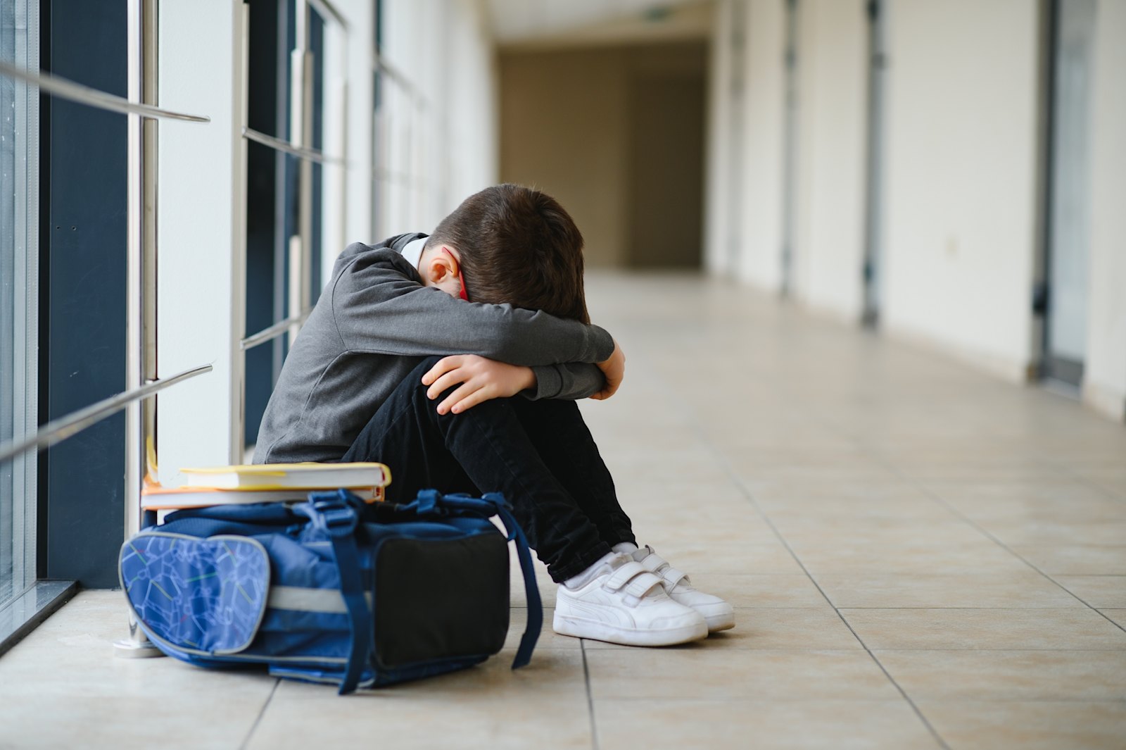 Premium Photo | Sad school boy sitting alone on floor at corridor.