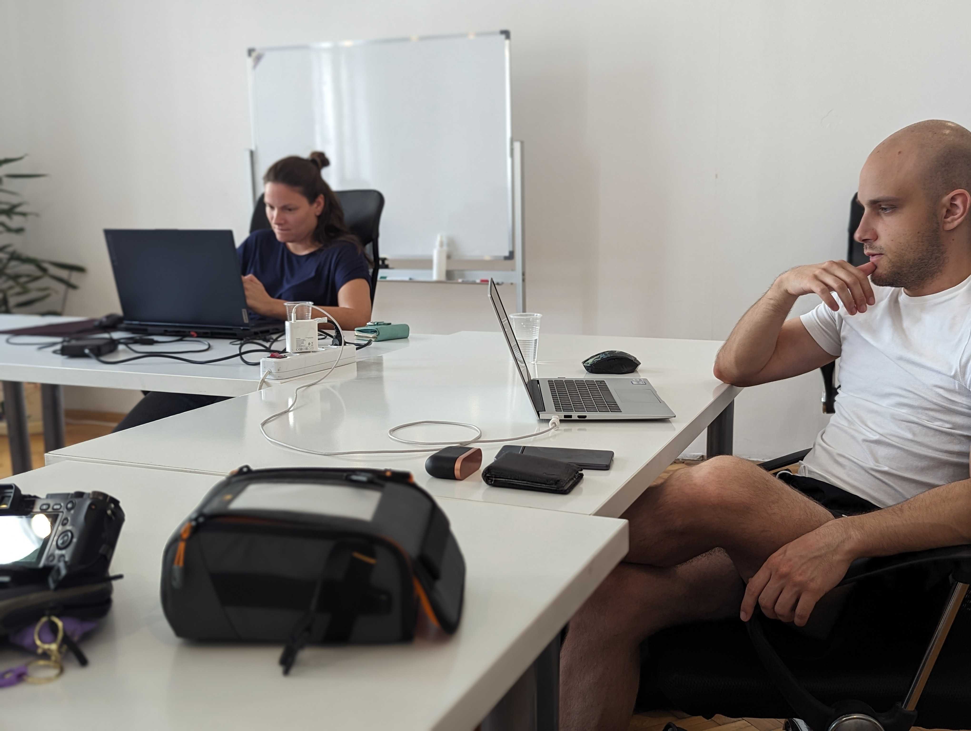 Two team members of FWRD agency collaborating and working on laptops in a clean, minimalist office workspace.