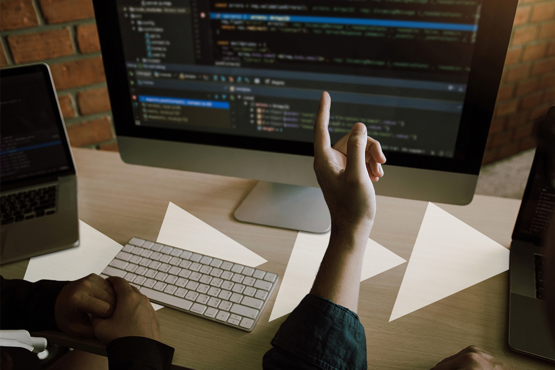 Two web developers discussing custom website development code on a desktop screen during collaboration.