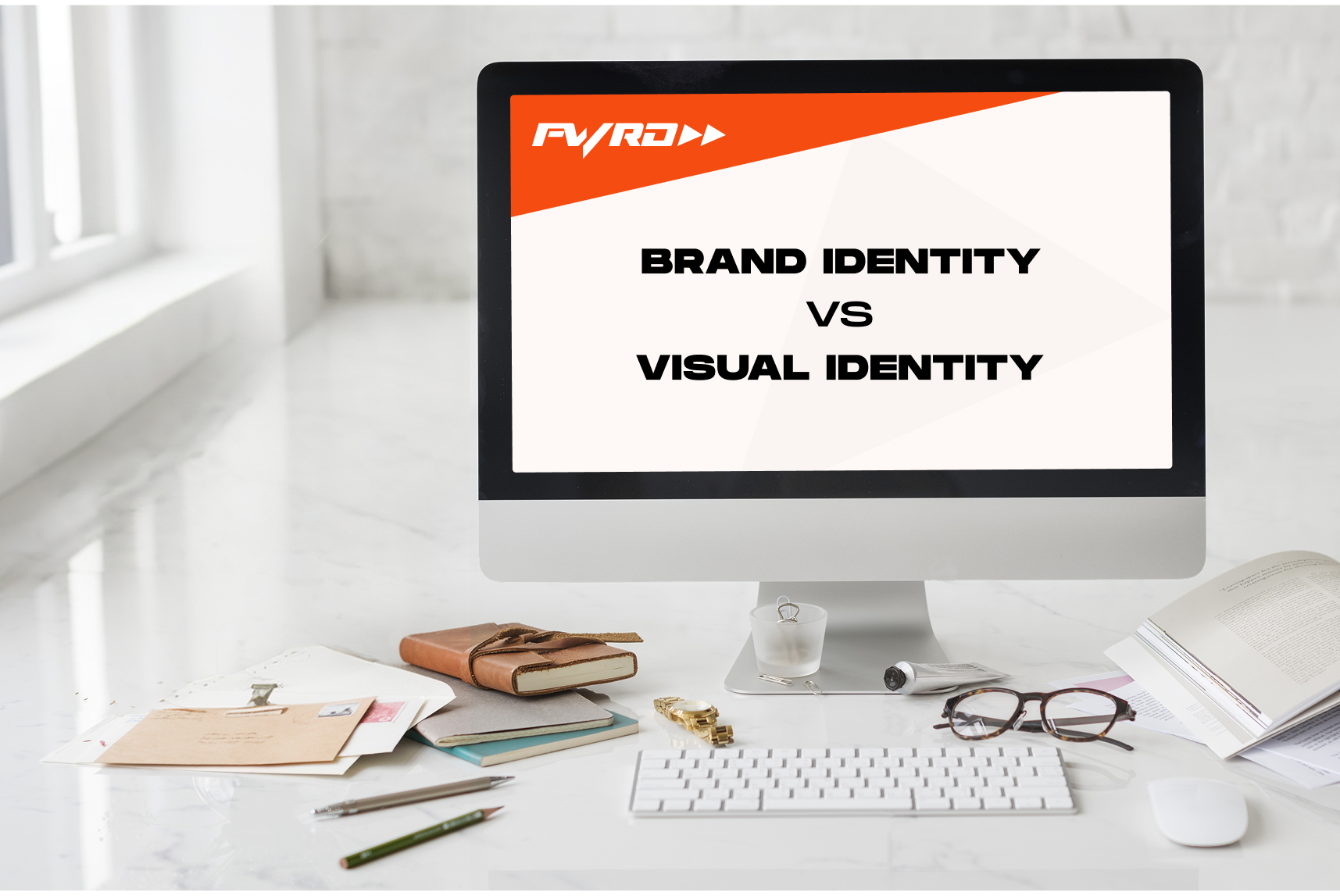 Computer screen showing brand identity versus visual identity concept in a minimalist creative workspace.