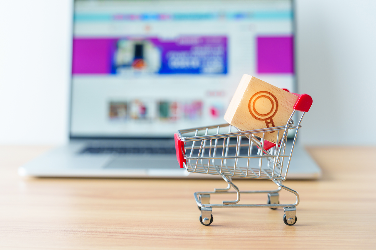 Miniature shopping cart with a wooden search icon block in front of FWRD Digital & Product ecommerce website.