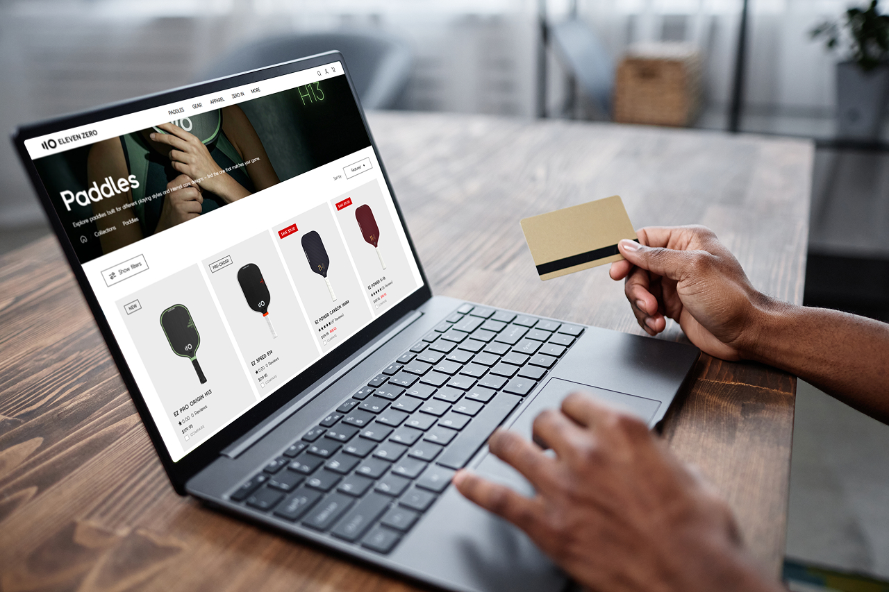 User completing an online purchase with a credit card on an ecommerce product listing page, showing categories and items on a laptop.