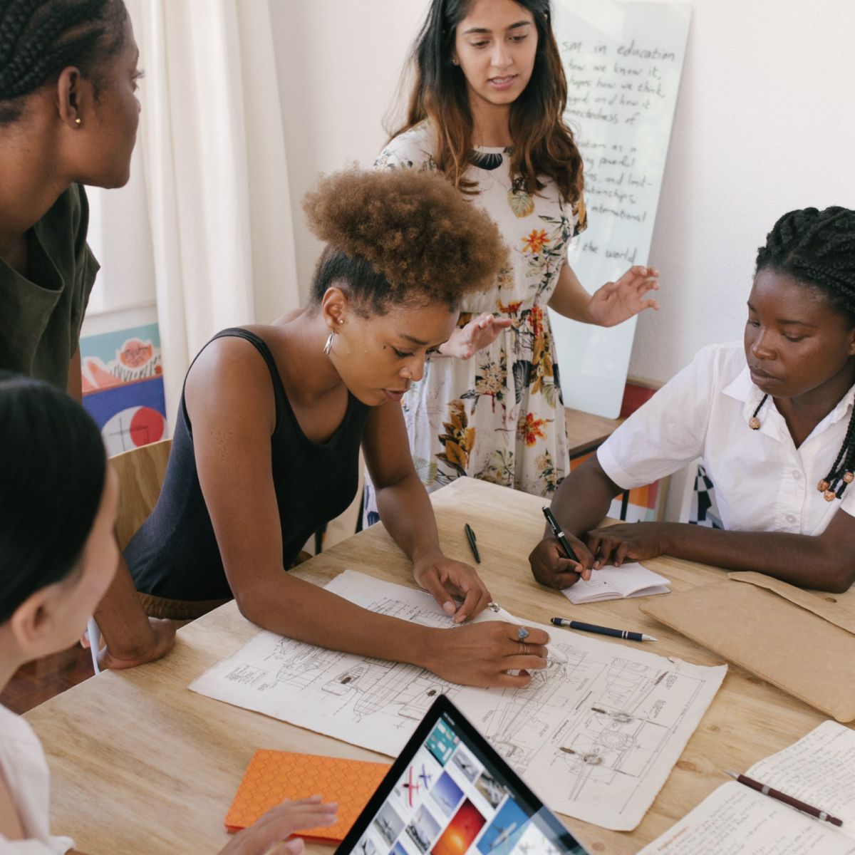 A group of people watching a lady drawing a schematic