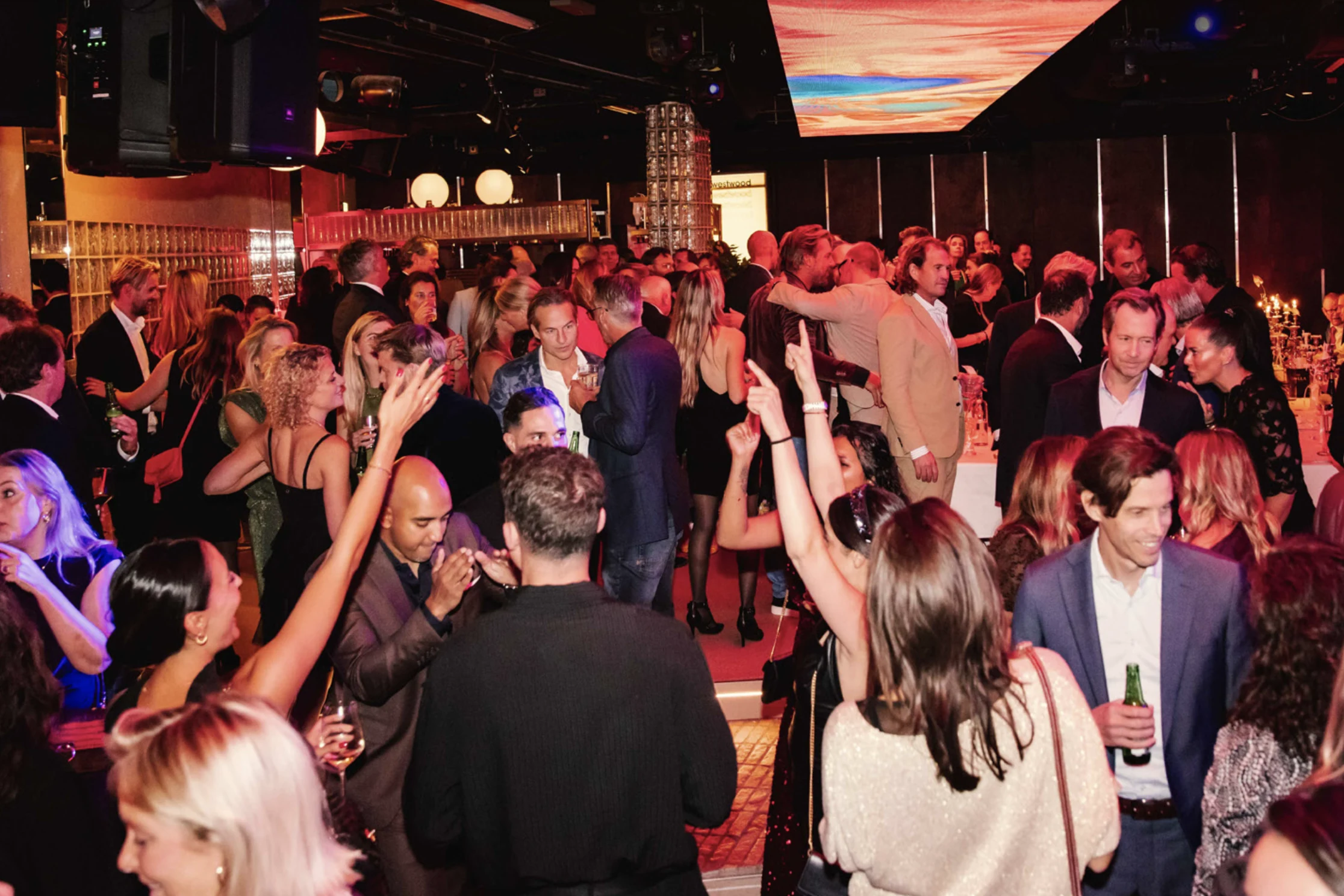 Feestende gasten tijdens een kerstborrel onder het LED-plafond van Westwood Den Haag