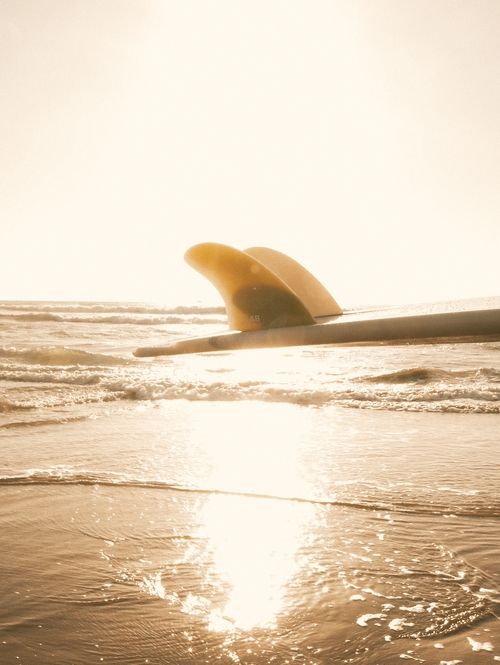 A yellow surfboard in the ocean.