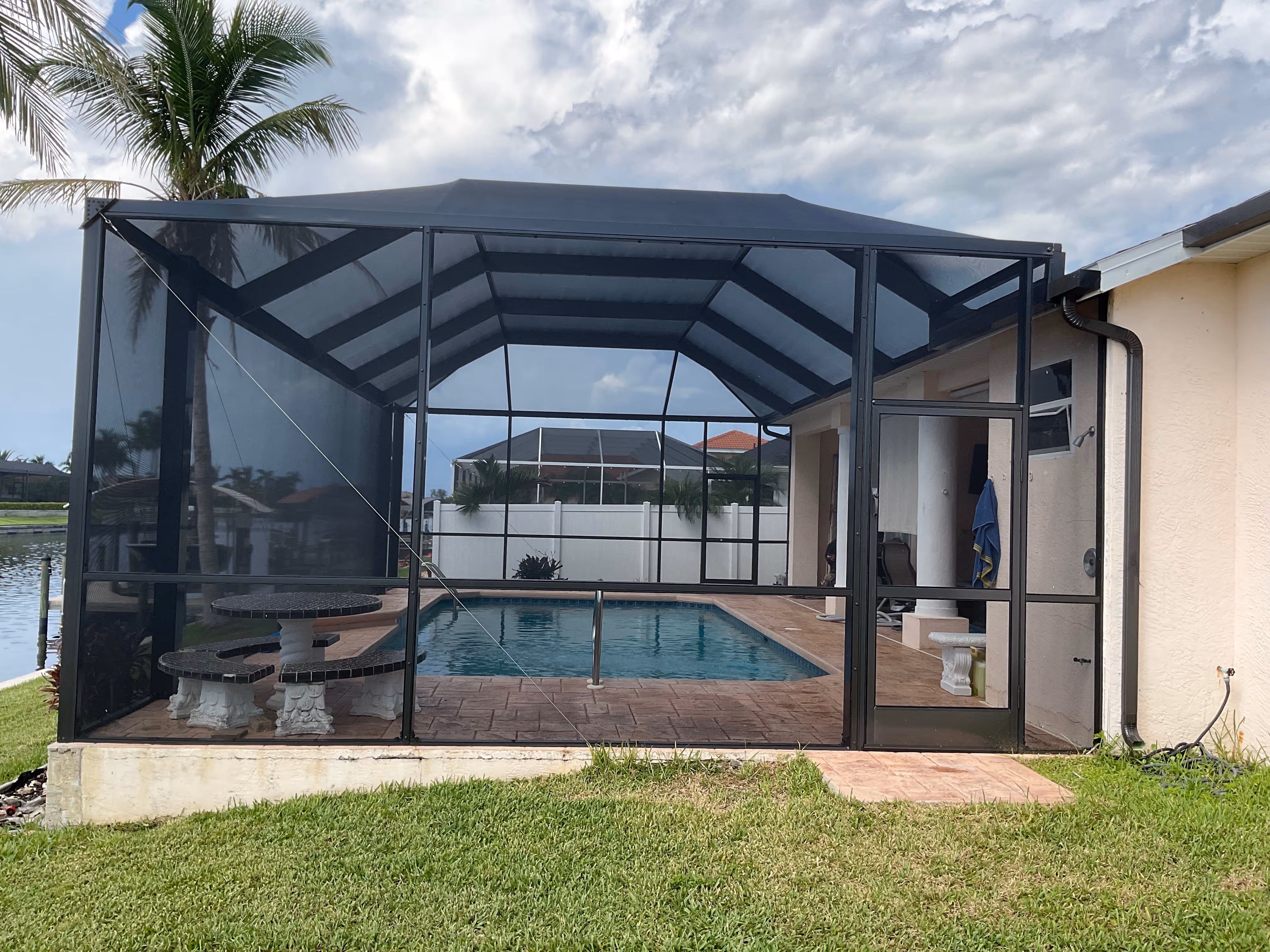 Dark bronze aluminum gable-roof pool screen enclosure interior, freeform pool, South Florida residential backyard with screened patio — AB Aluminum & Screens