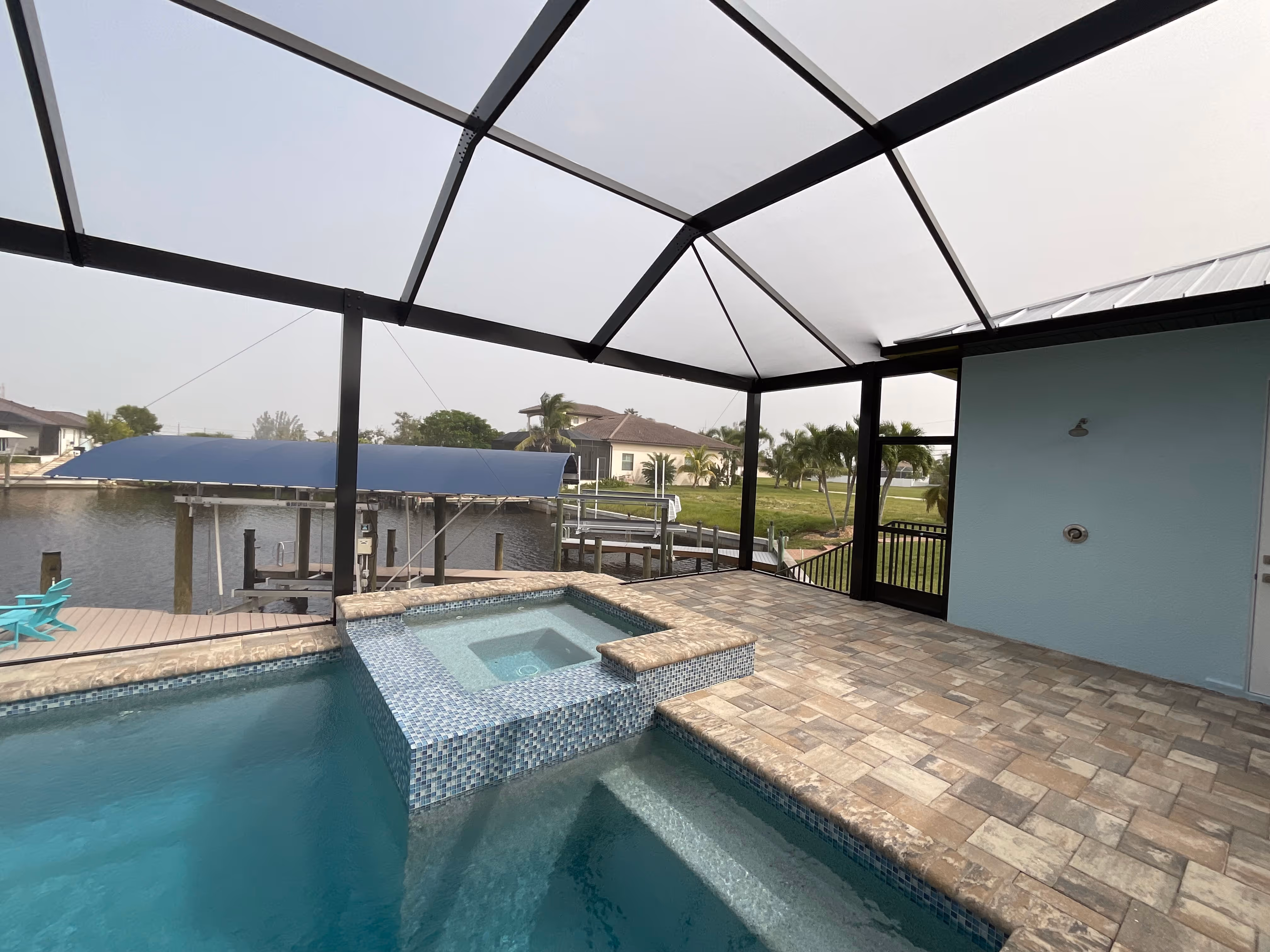Dark bronze aluminum pool screen enclosure interior, freeform pool with paver deck, South Florida residential backyard — AB Aluminum & Screens