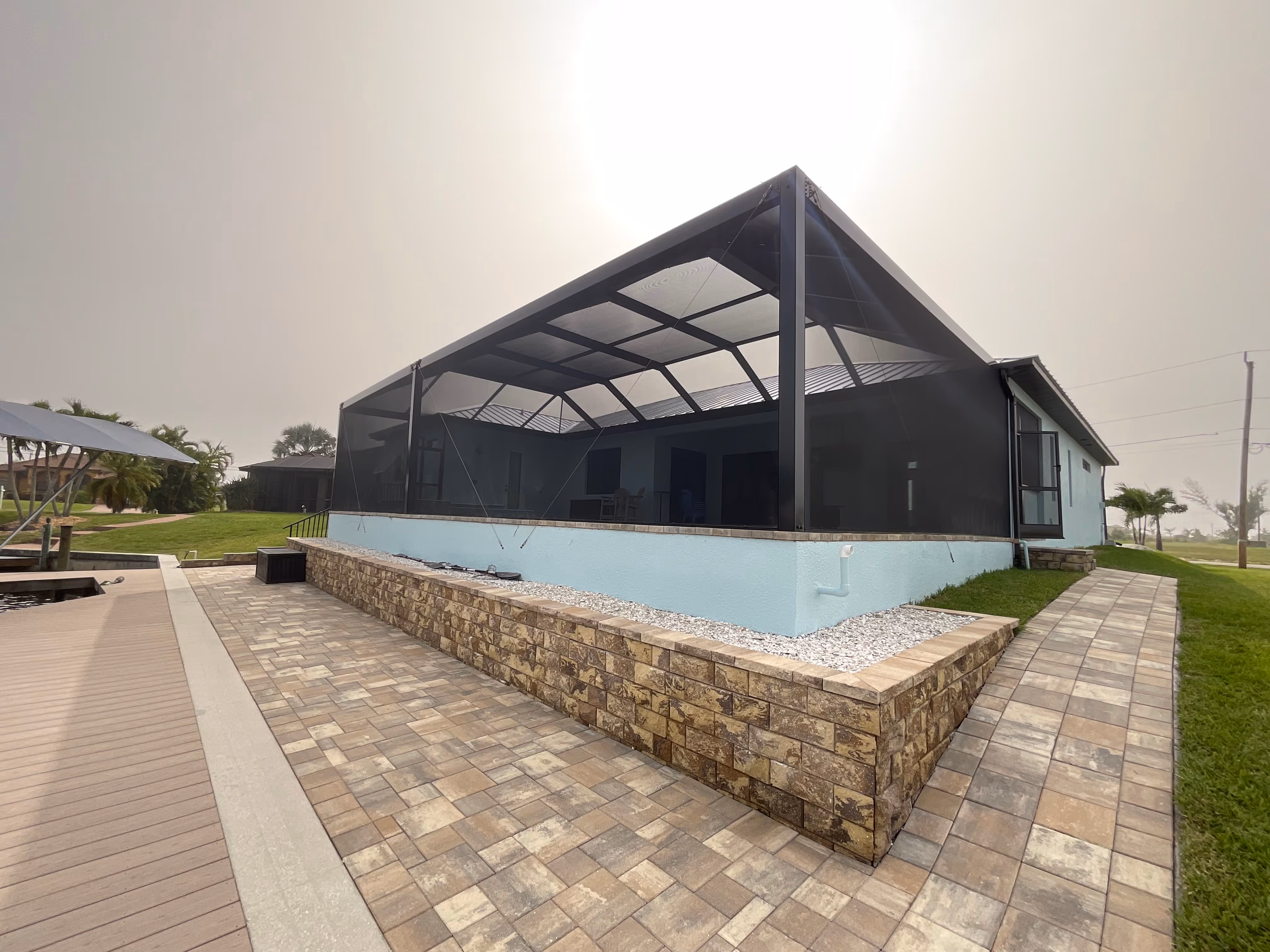 Dark bronze aluminum pool screen enclosure with gable roof, screened pool area, paver deck, South Florida residential installation — AB Aluminum & Screens
