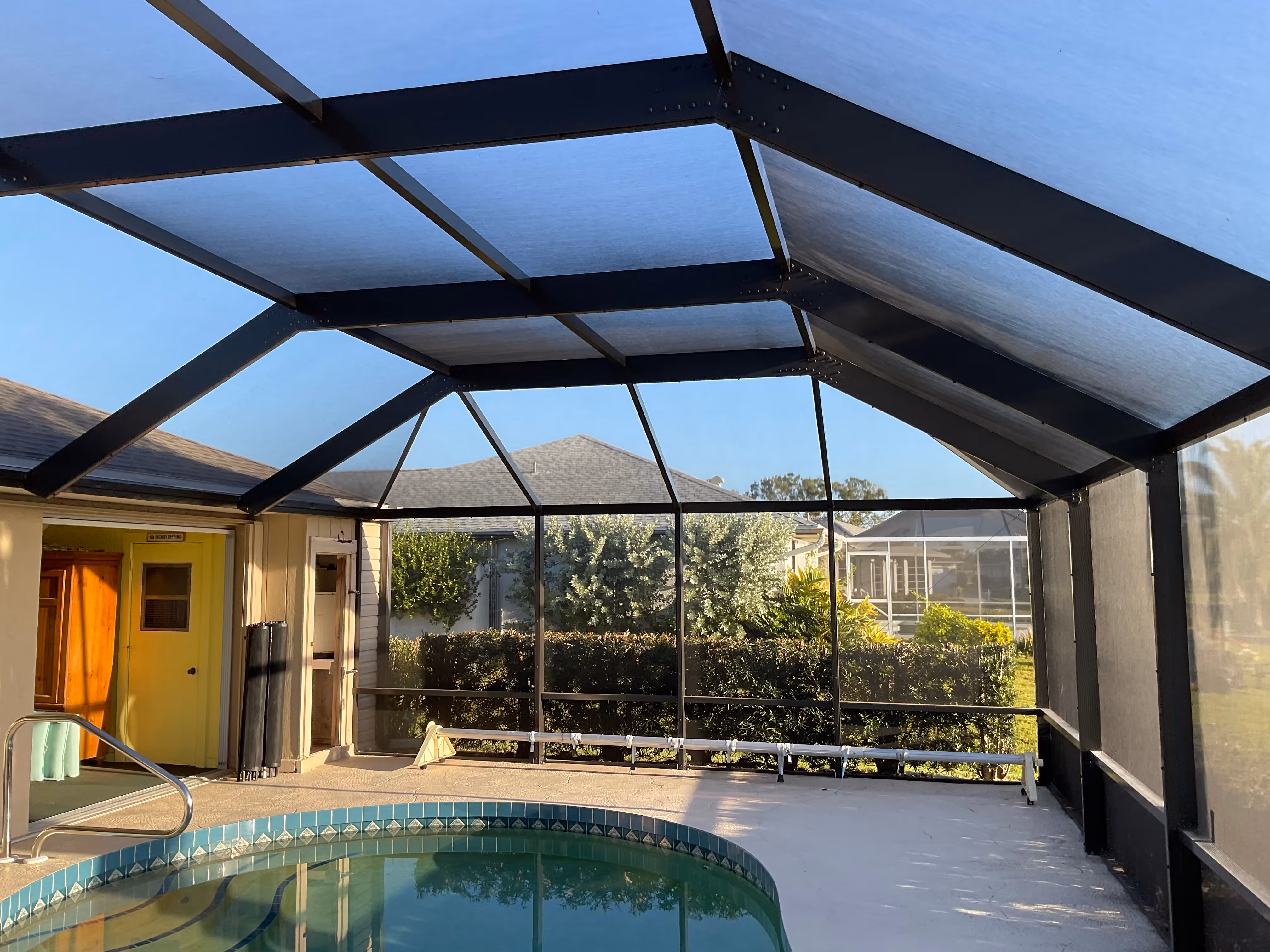 Dark bronze aluminum pool screen enclosure with screened pool area and paver deck, South Florida residential backyard — AB Aluminum & Screens