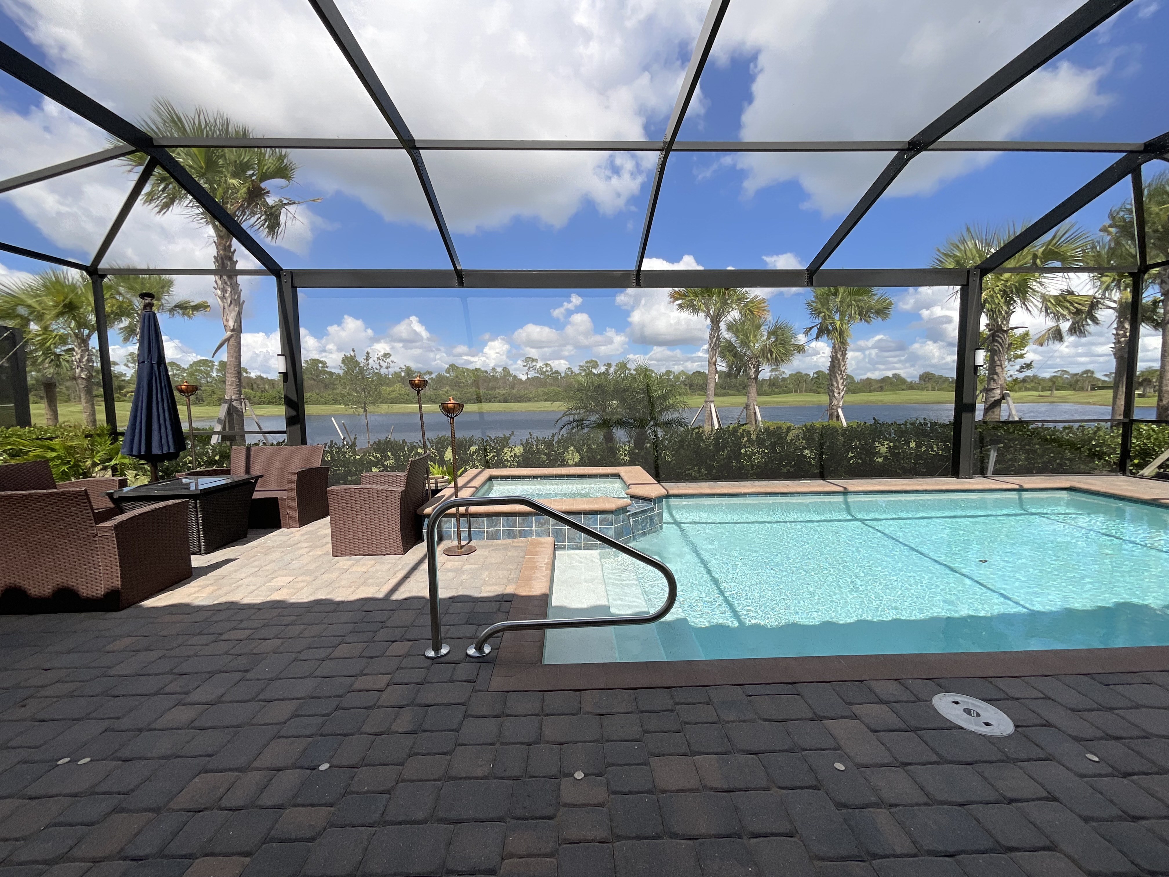 Dark bronze aluminum pool screen enclosure interior, screened pool area with paver deck, South Florida residential backyard — AB Aluminum & Screens