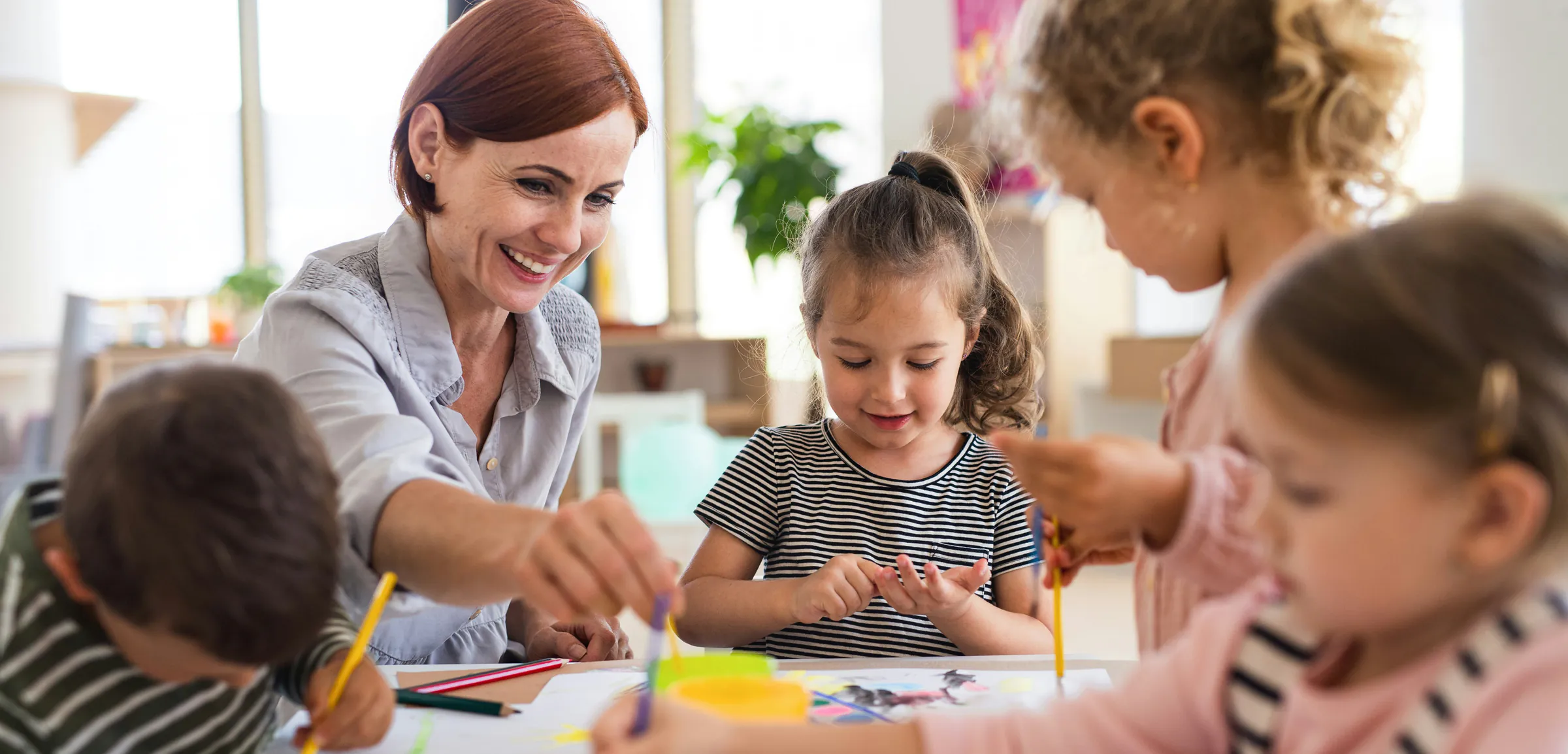 Professionnelle de crèche animant une activité de dessin avec des enfants