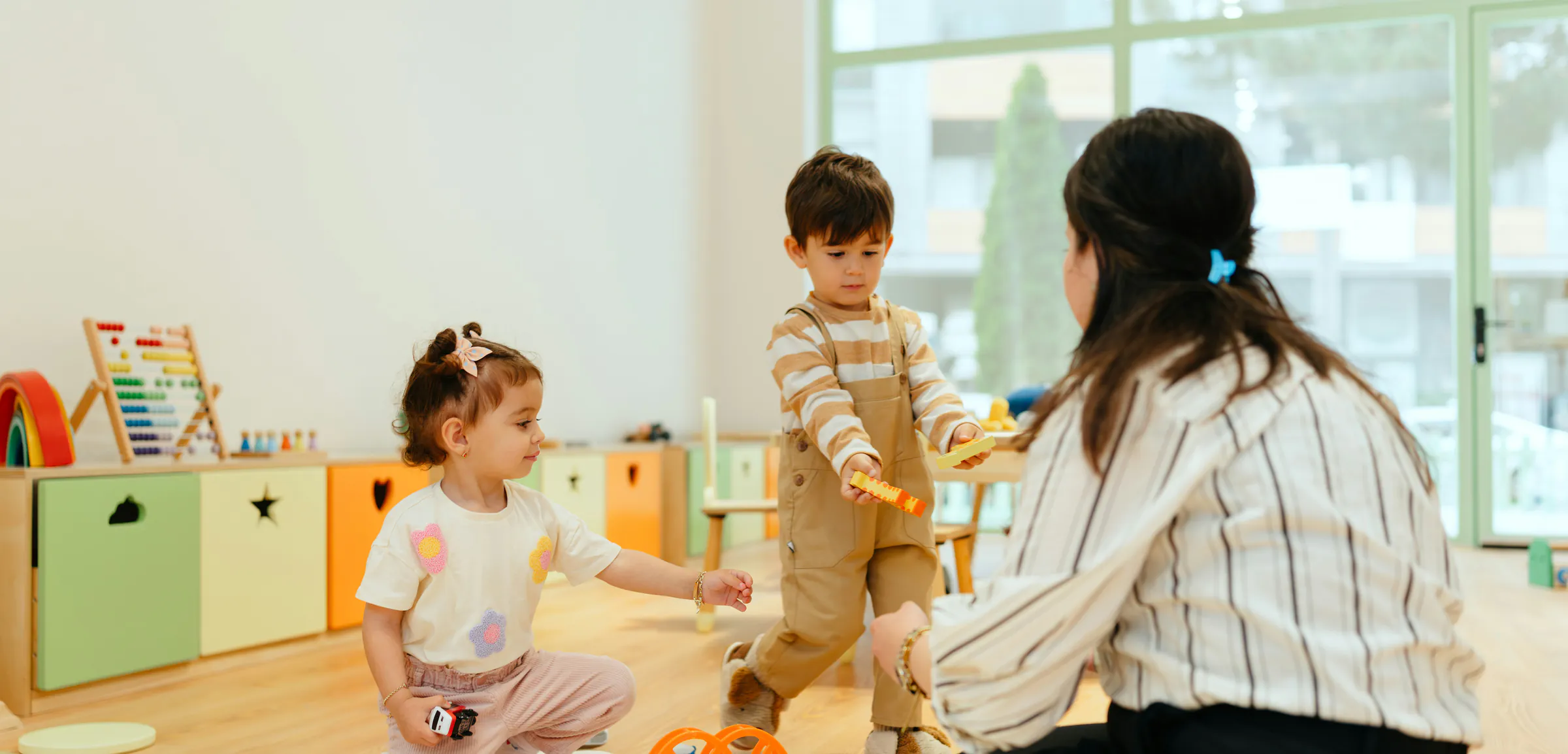 Professionnelle de crèche jouant avec deux jeunes enfants