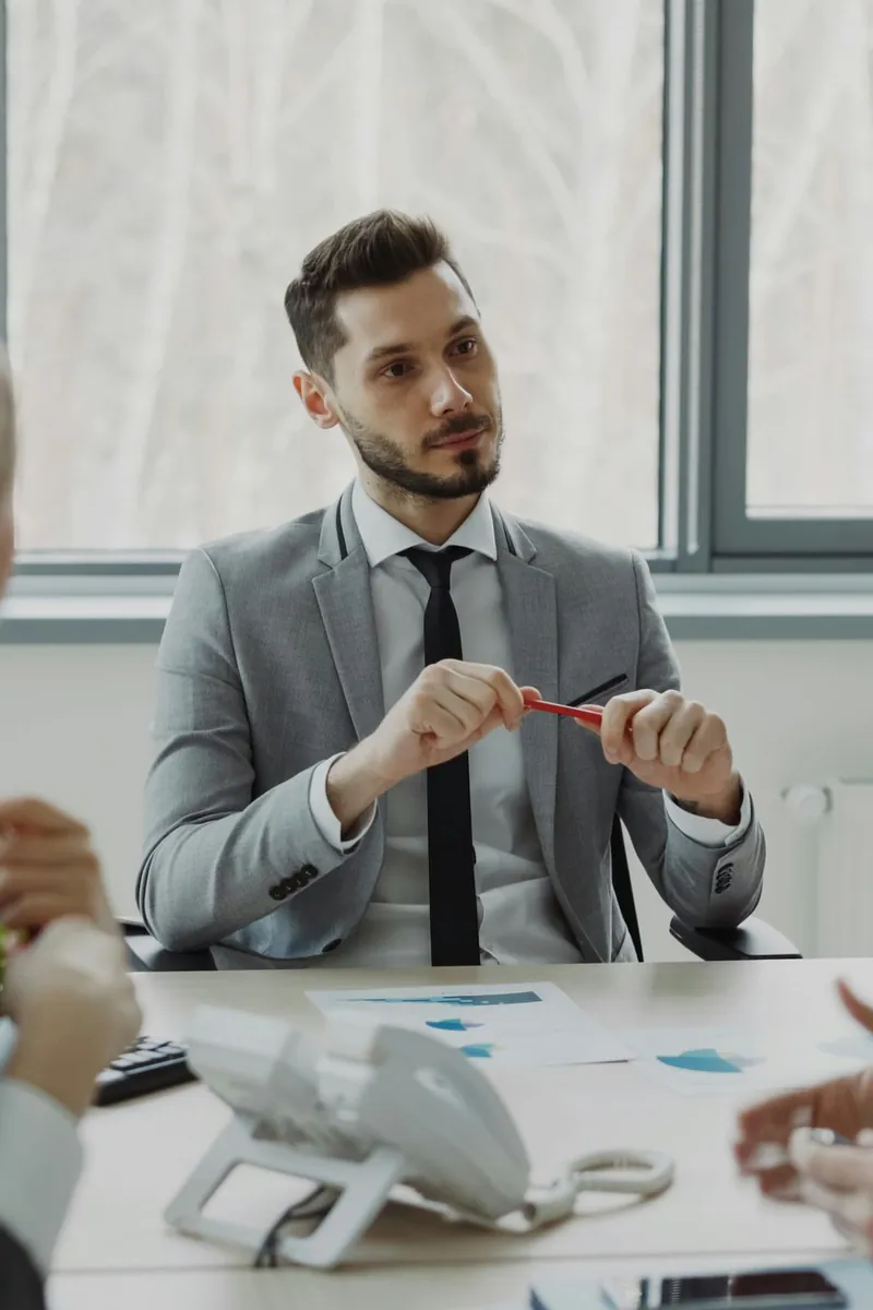 Un manager en costume échange avec trois collègues autour d'un bureau couvert de documents