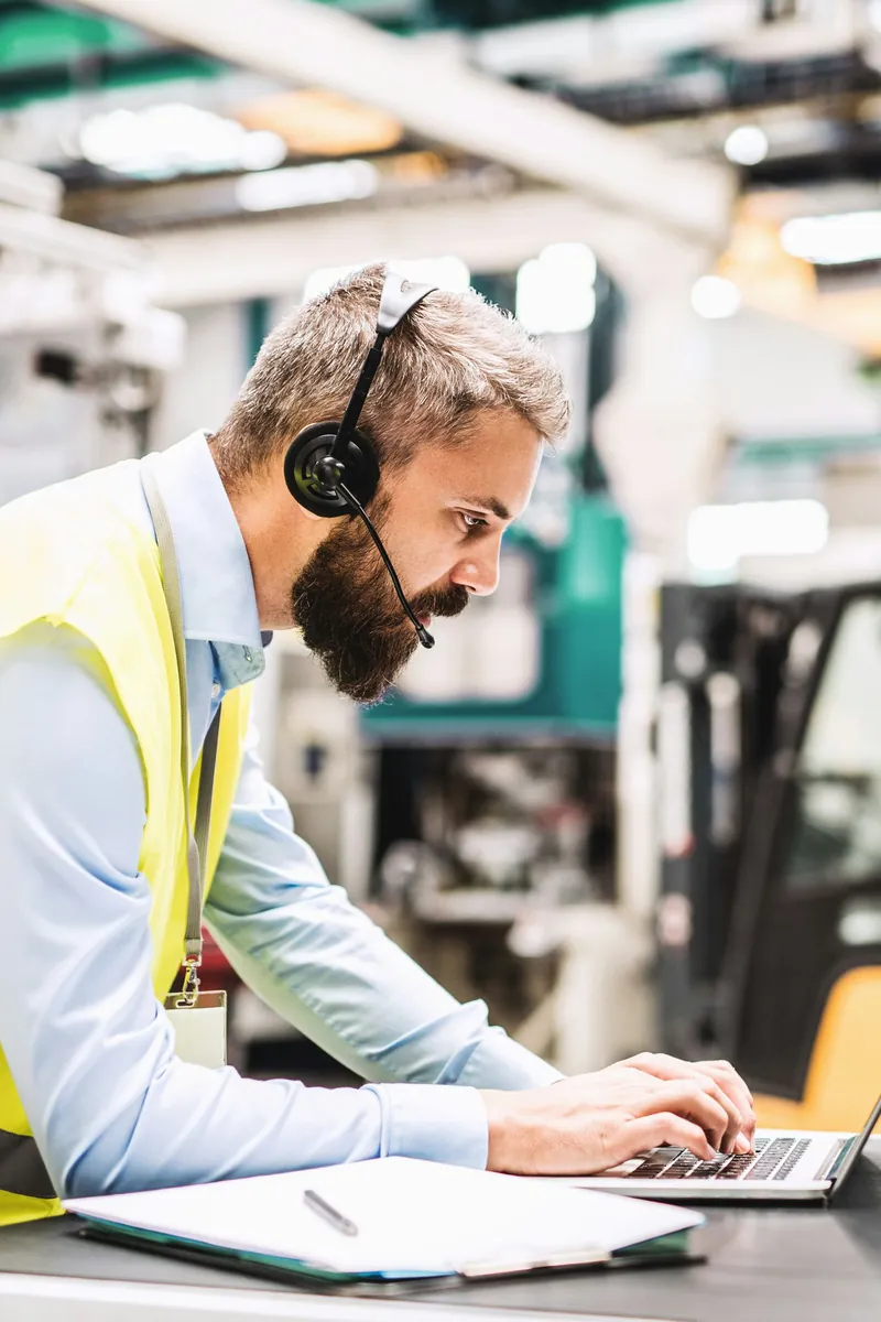 Responsable d'exploitation au casque-micro travaillant sur un ordinateur portable