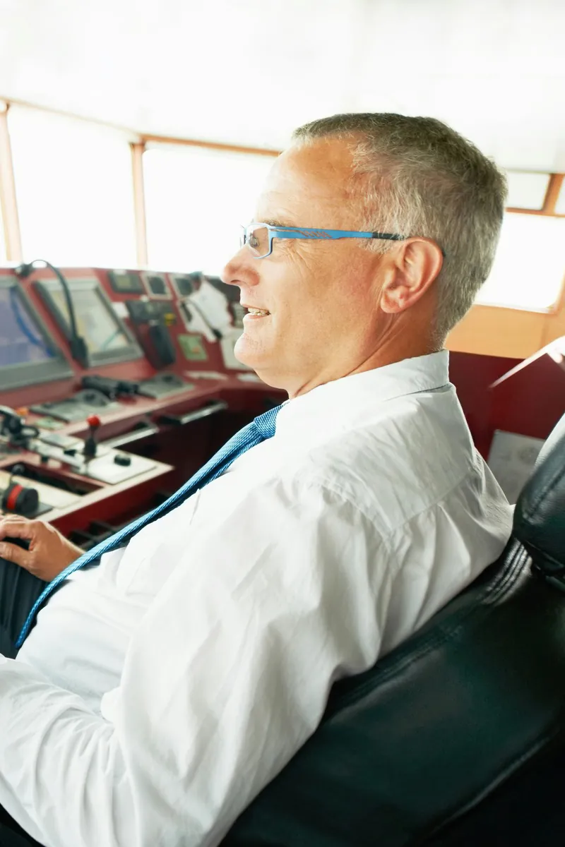 Responsable assis sur la passerelle d'un navire devant les écrans de navigation