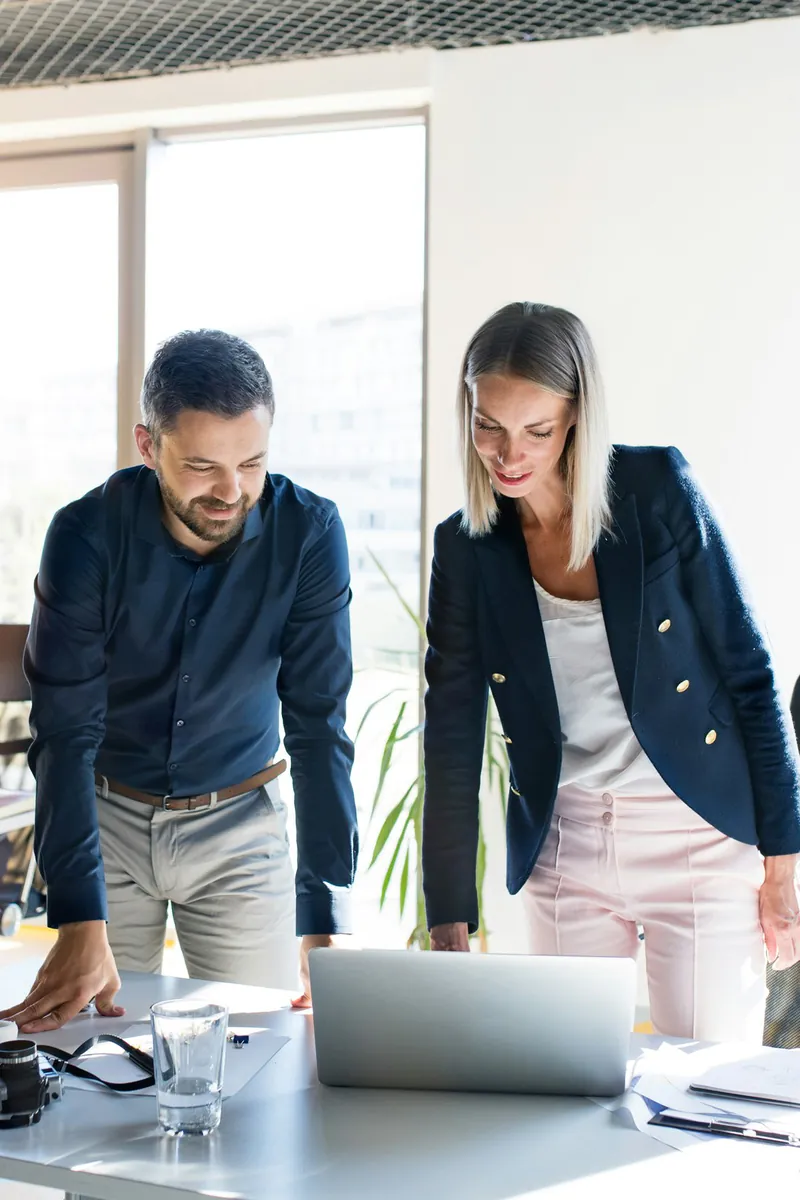 Chef de mission et collaboratrice examinant un dossier sur ordinateur portable