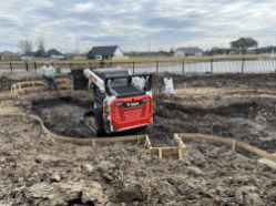 Custom pool construction company digging pool with excavator in a backyard pool build project