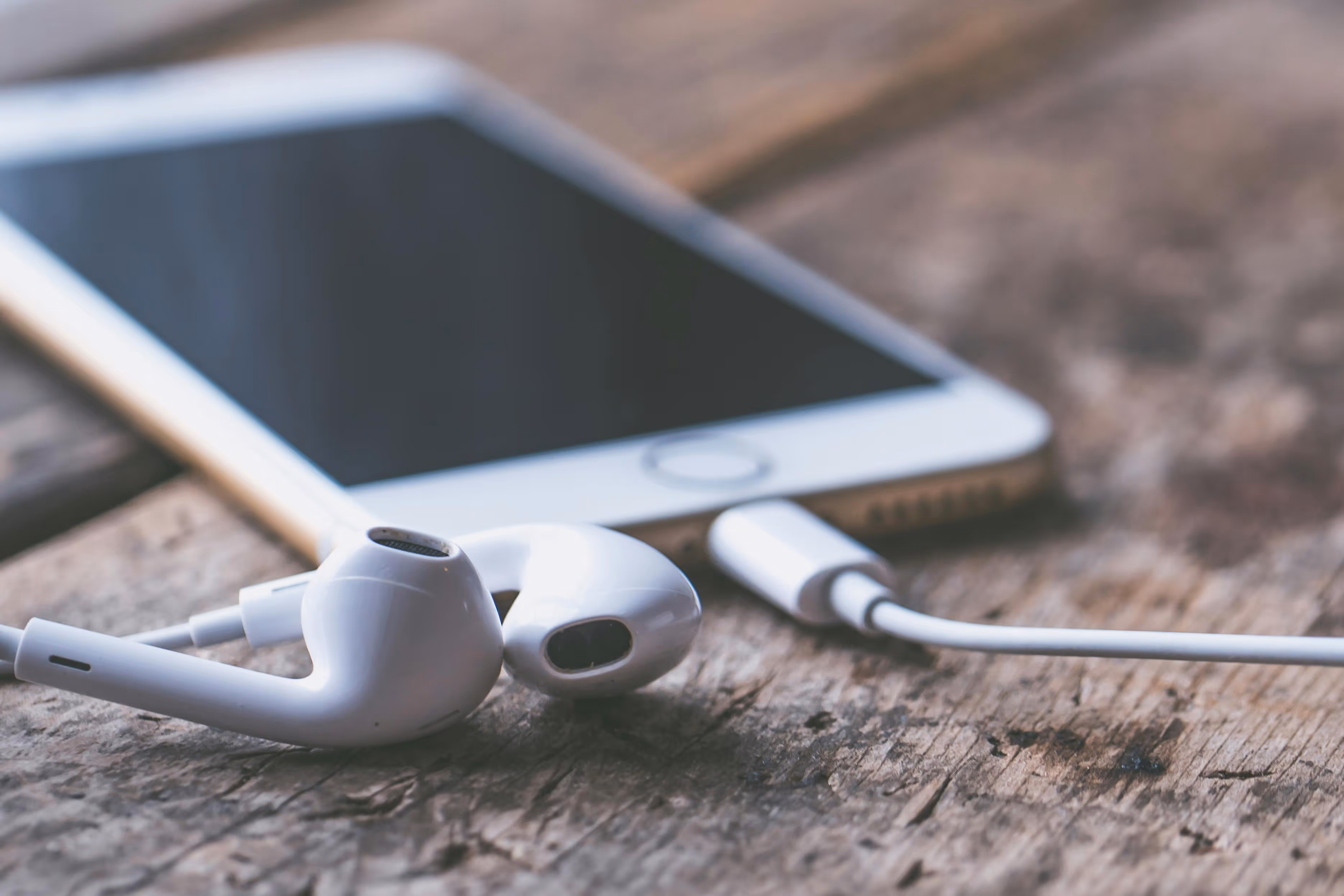A smartphone with earbuds plugged in, representing the permeation of music in mobile devices.