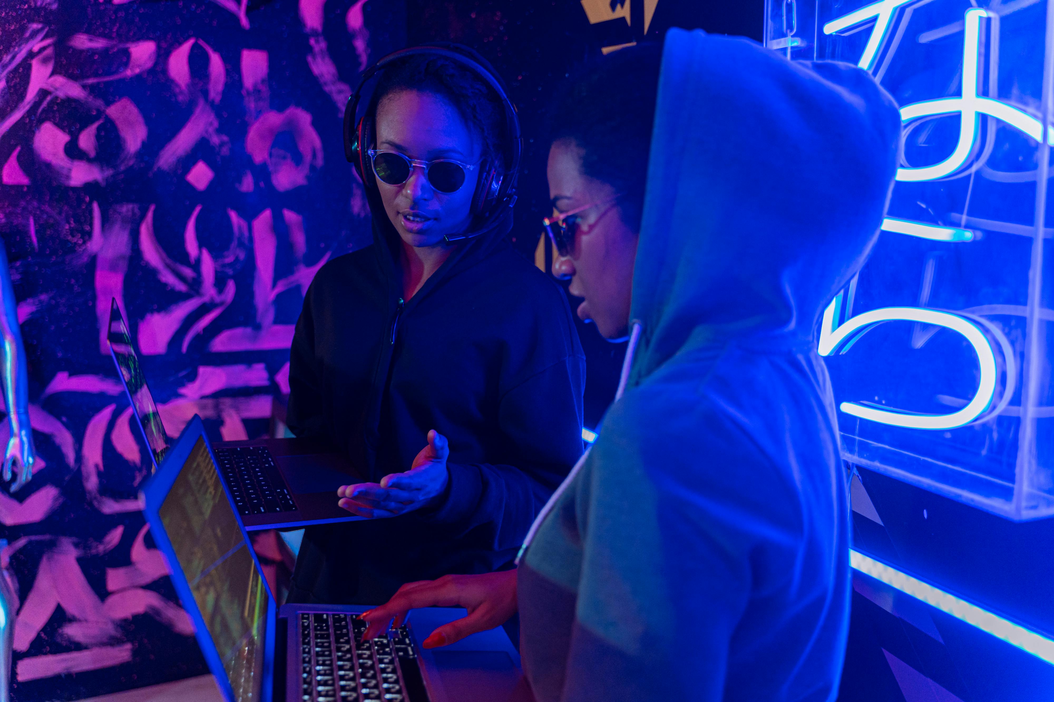 Two women working on music on laptops in a studio - signifying hip-hop's shift to AI.